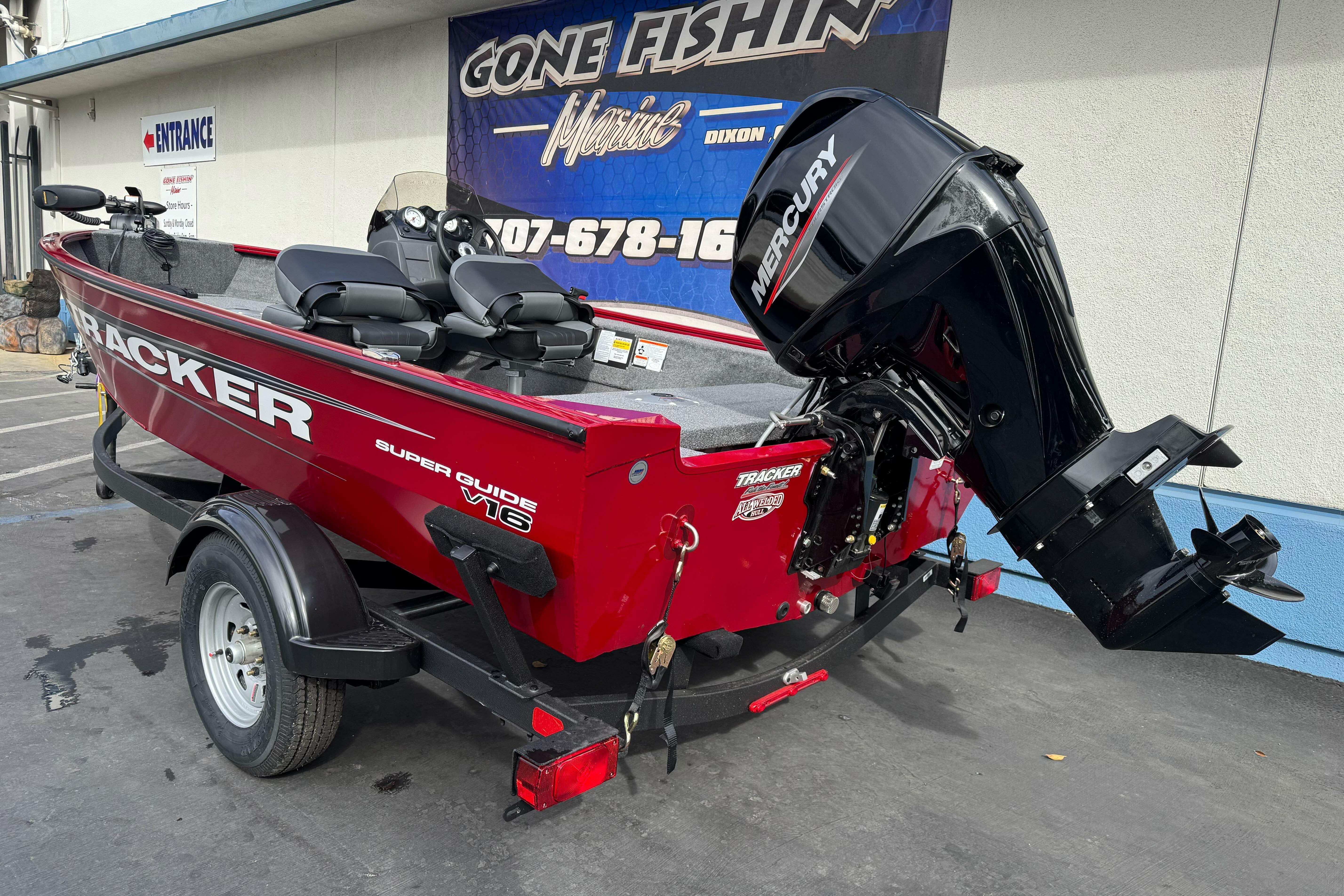 2026 Tracker Super Guide V-16 SC boat with Mercury outboard motor, parked at a dealership.