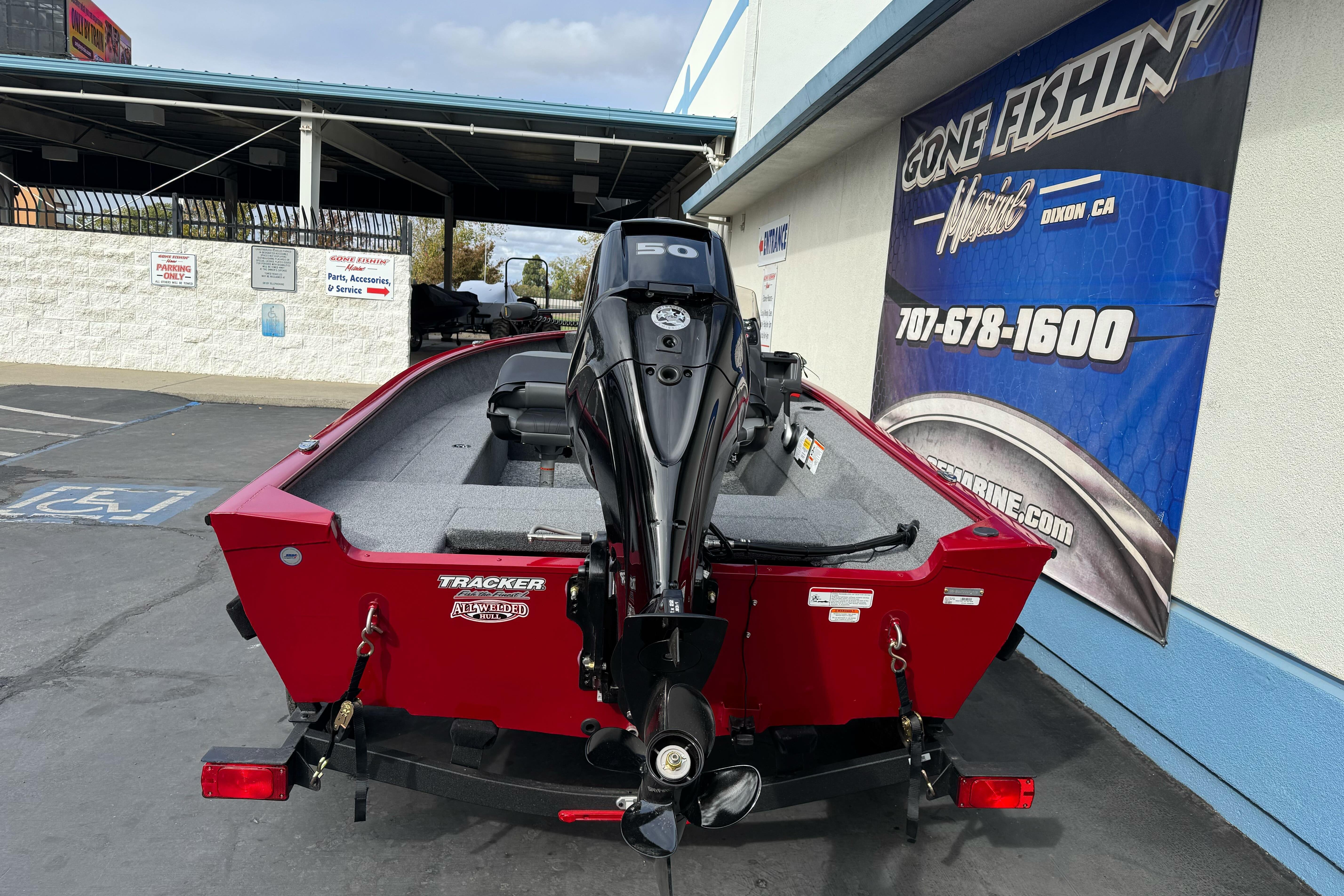 2026 Tracker Super Guide V-16 SC boat, red exterior, parked at dealership.