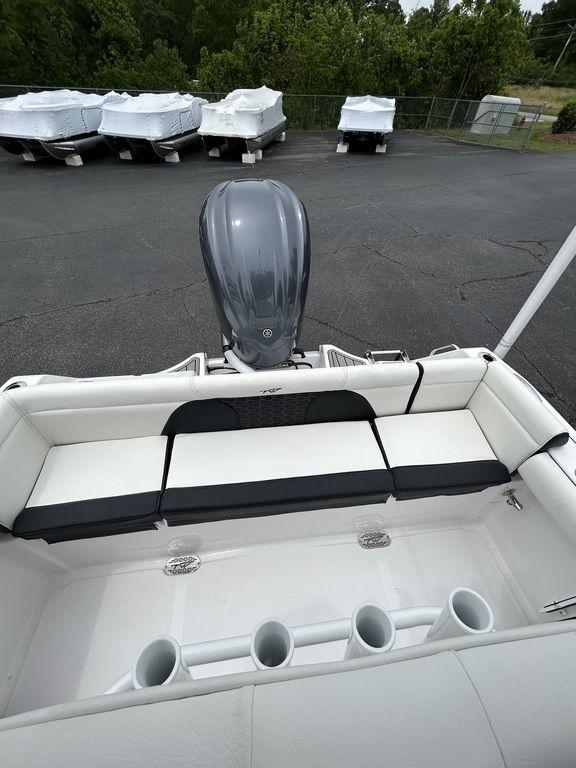 2025 Tidewater 232 LXF boat with cushioned seating and outboard motor in a parking area.