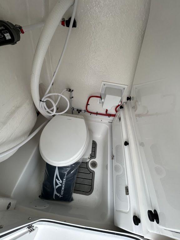 2025 Tidewater 232 LXF boat interior with marine toilet and storage area.
