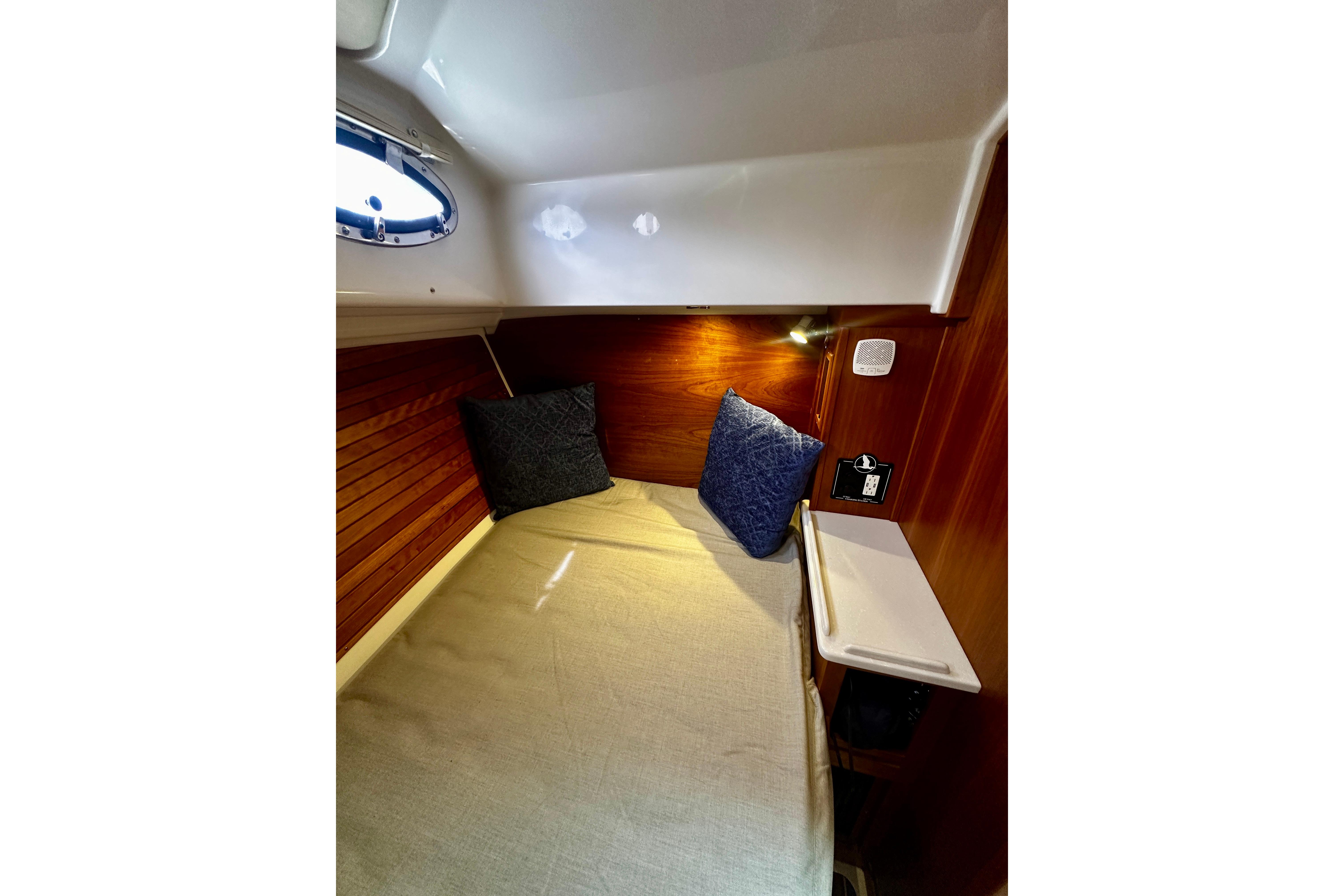 2019 Back Cove 37 cabin interior with cozy bed, wooden paneling, and porthole window.