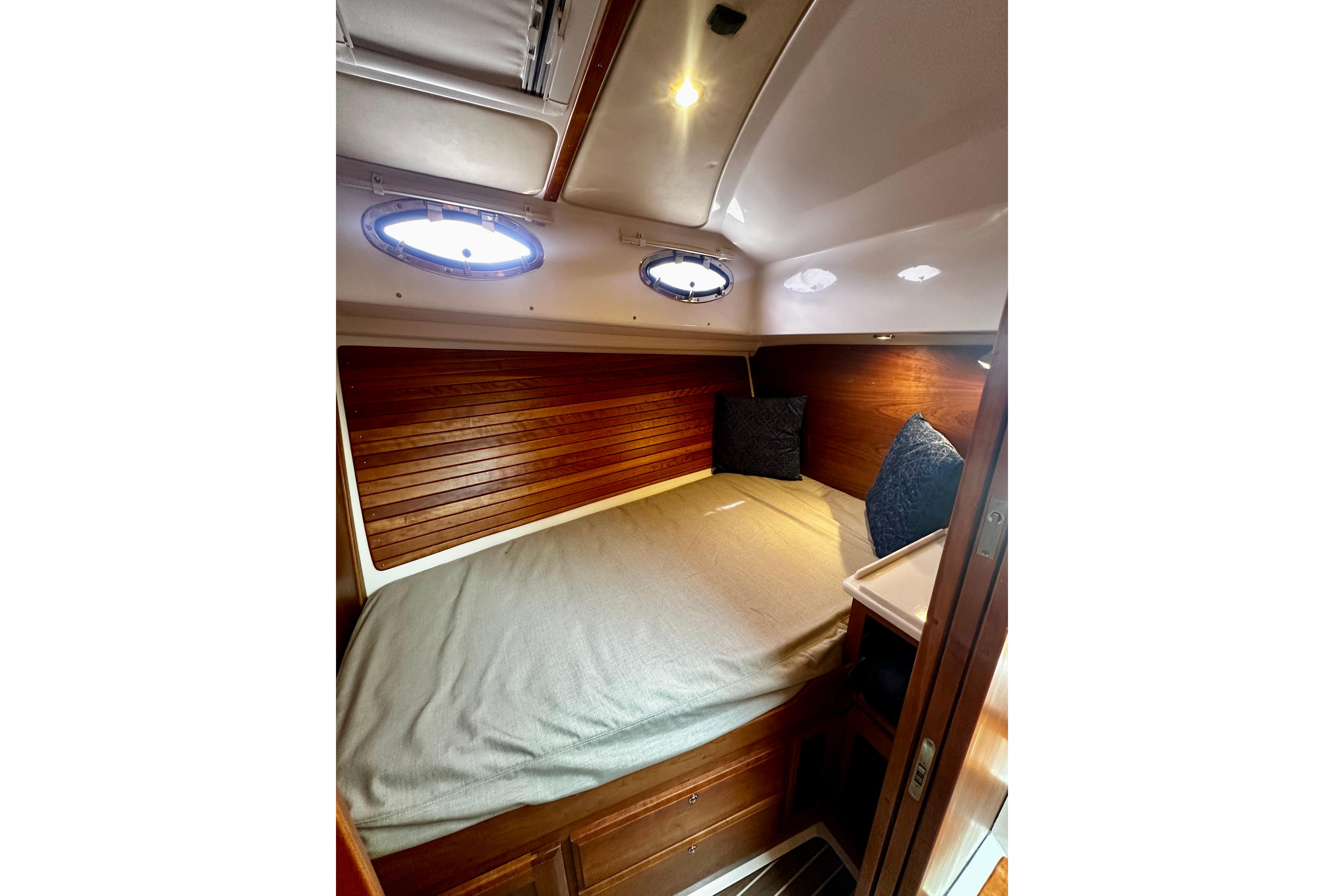 Cozy cabin interior of 2019 Back Cove 37 yacht with wood paneling and portholes.