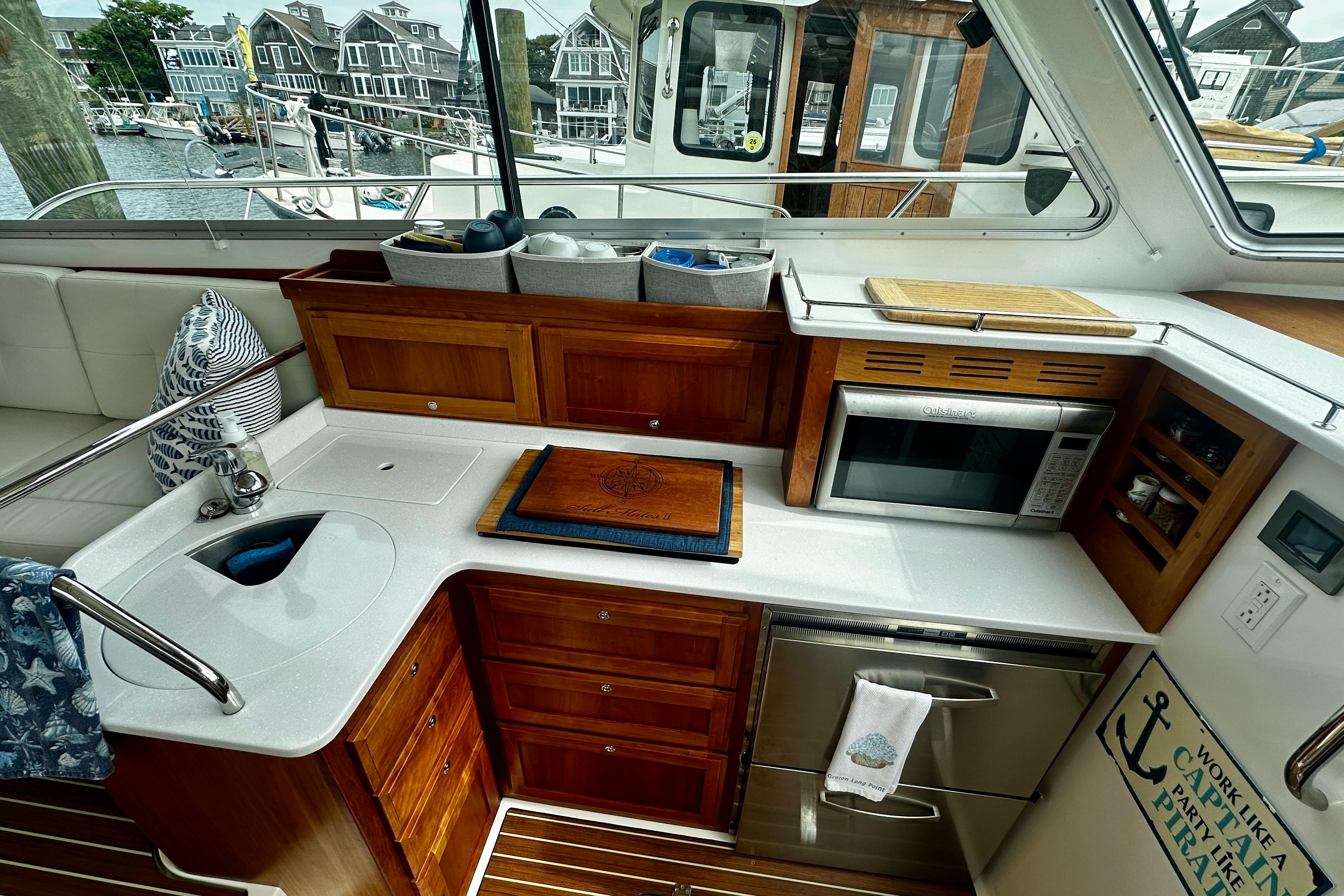 2019 Back Cove 37 yacht kitchen with wooden cabinetry, sink, and microwave, overlooking marina.
