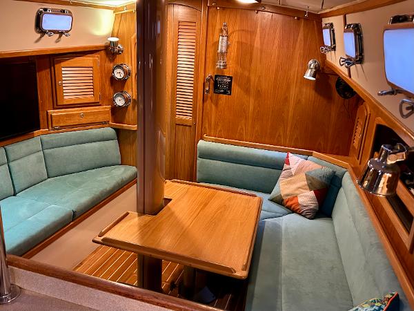 Cozy interior of 1999 Pacific Seacraft 40 Voyagemaker sailboat with wood finish and teal seating.