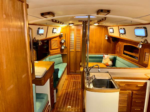 Interior of 1999 Pacific Seacraft 40 Voyagemaker yacht with wood finish and teal seating.
