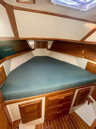 1999 Pacific Seacraft 40 Voyagemaker cabin with wooden interior and cozy bed.