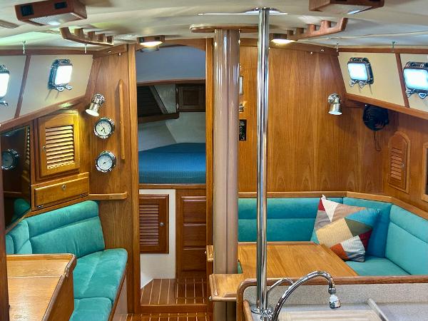 Interior of 1999 Pacific Seacraft 40 Voyagemaker yacht with wood finish and teal seating.
