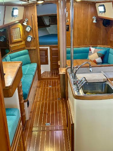 1999 Pacific Seacraft 40 Voyagemaker interior with wood finish, teal seating, and kitchen sink.