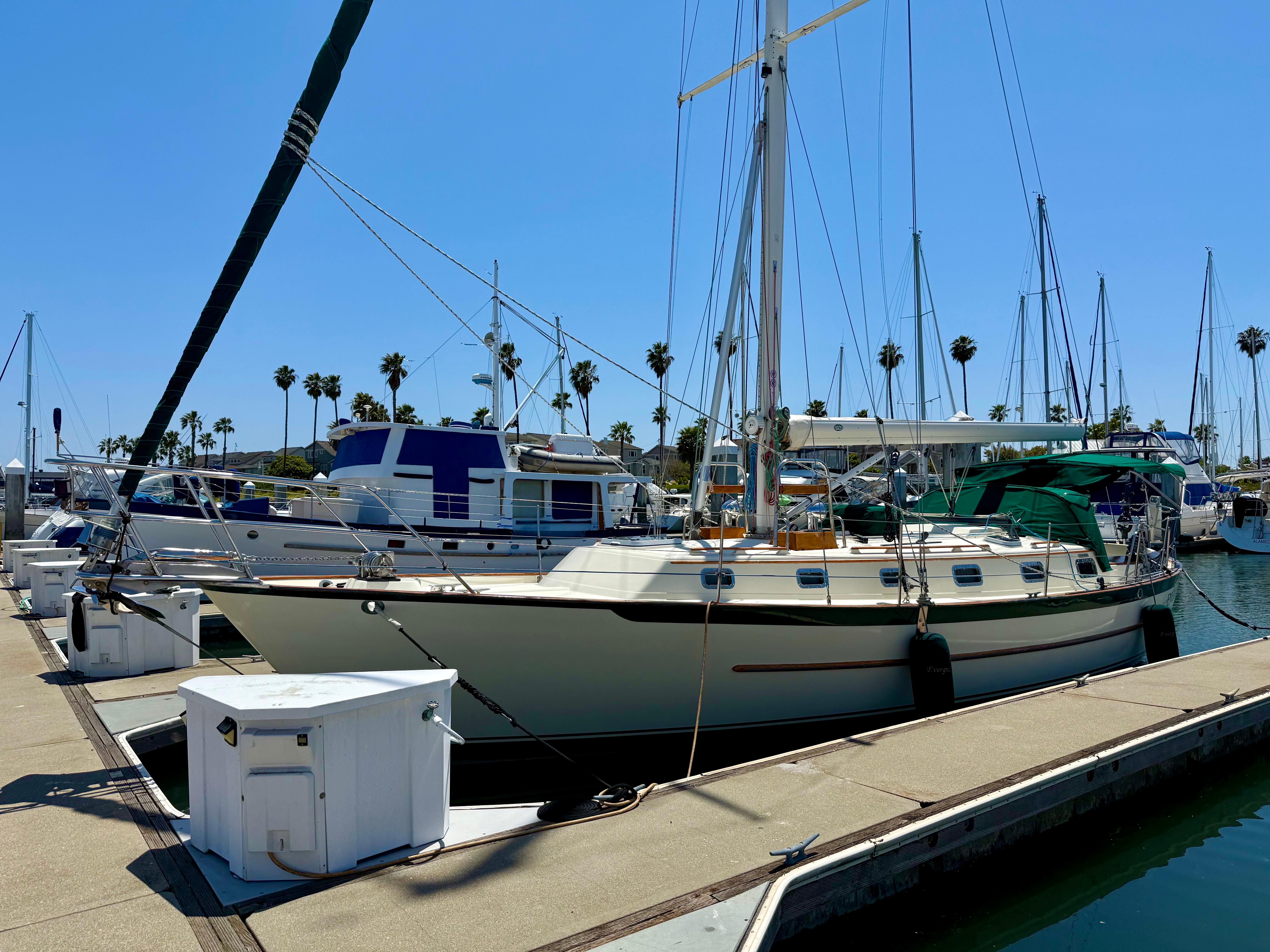 Sailboat docked at marina, 1999 Pacific Seacraft 40 Voyagemaker, clear sky, palm trees in background.