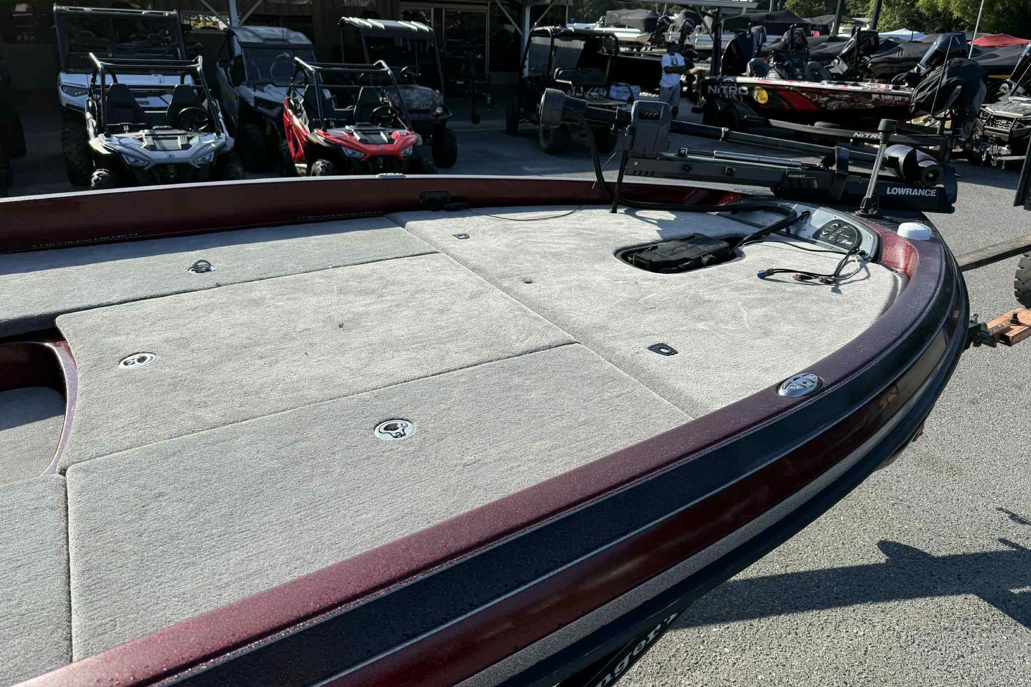 2008 Ranger Z520 Comanche boat deck with fishing equipment, parked near off-road vehicles.