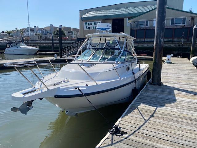 2005 Boston Whaler 275 Conquest docked at marina under clear sky.