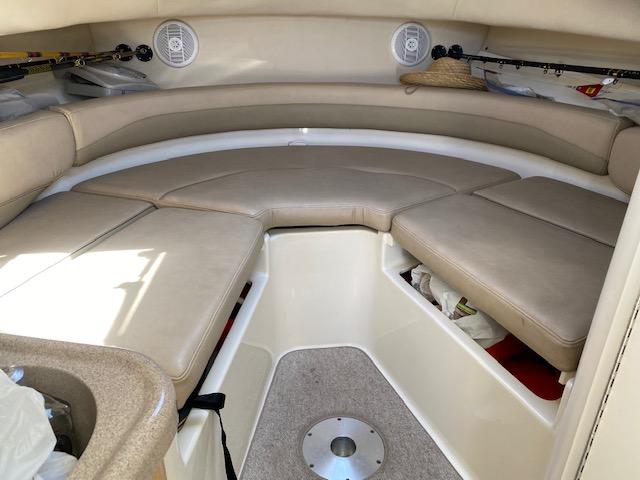 2005 Boston Whaler 275 Conquest cabin interior with beige seating and storage compartments.