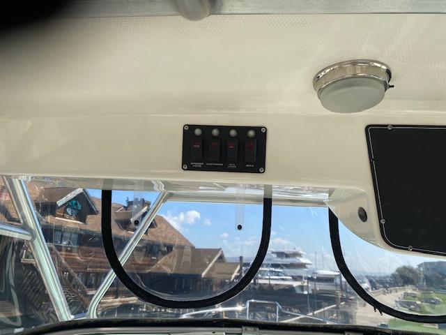 Interior view of 2005 Boston Whaler 275 Conquest boat with control panel and window.