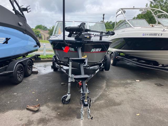 2014 Tracker Pro Guide V-16 WT boat on trailer, parked between two other boats.