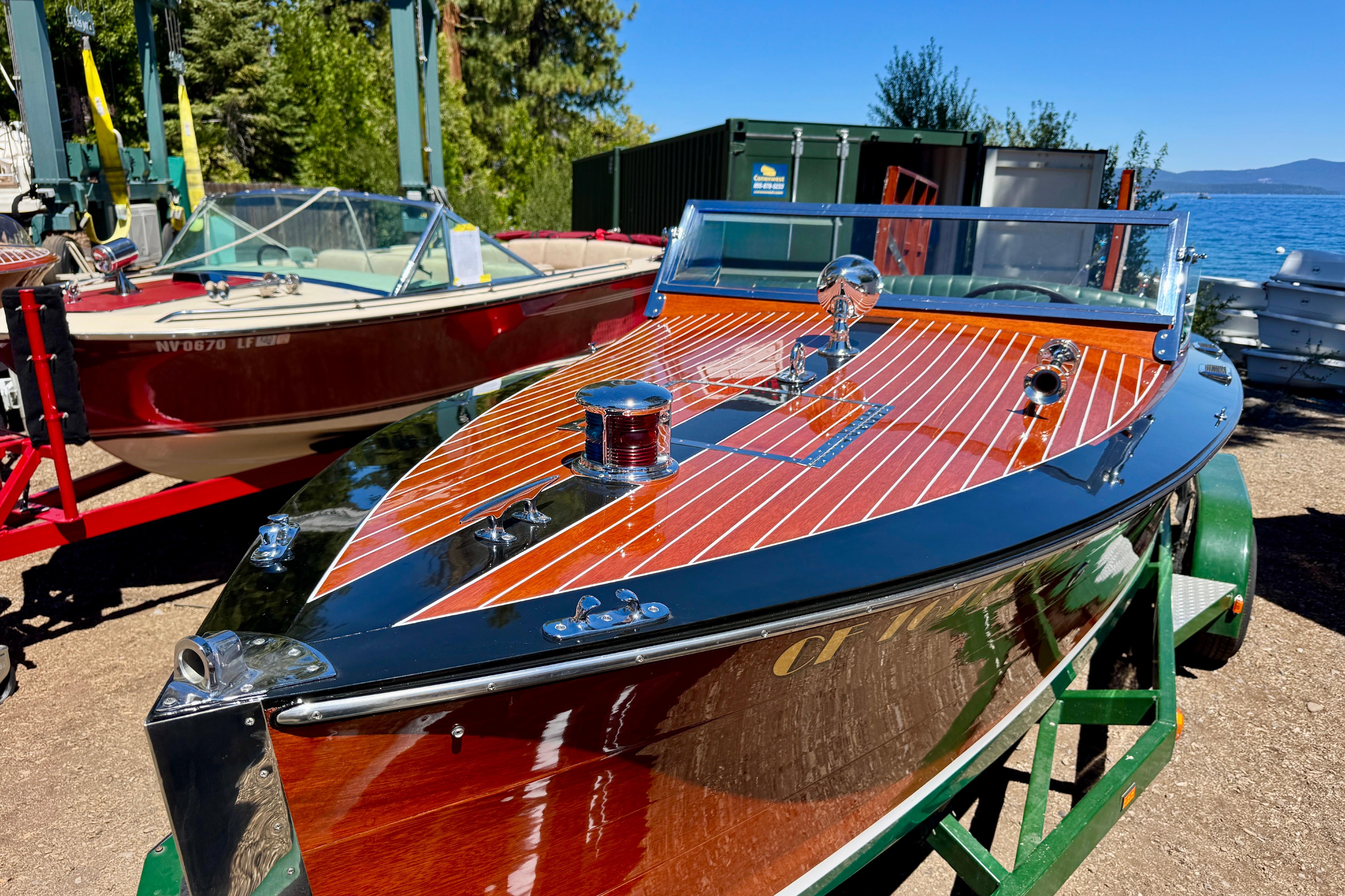 1987 Grand Craft Triple Cockpit Runabout, polished wood finish, docked near a lake.