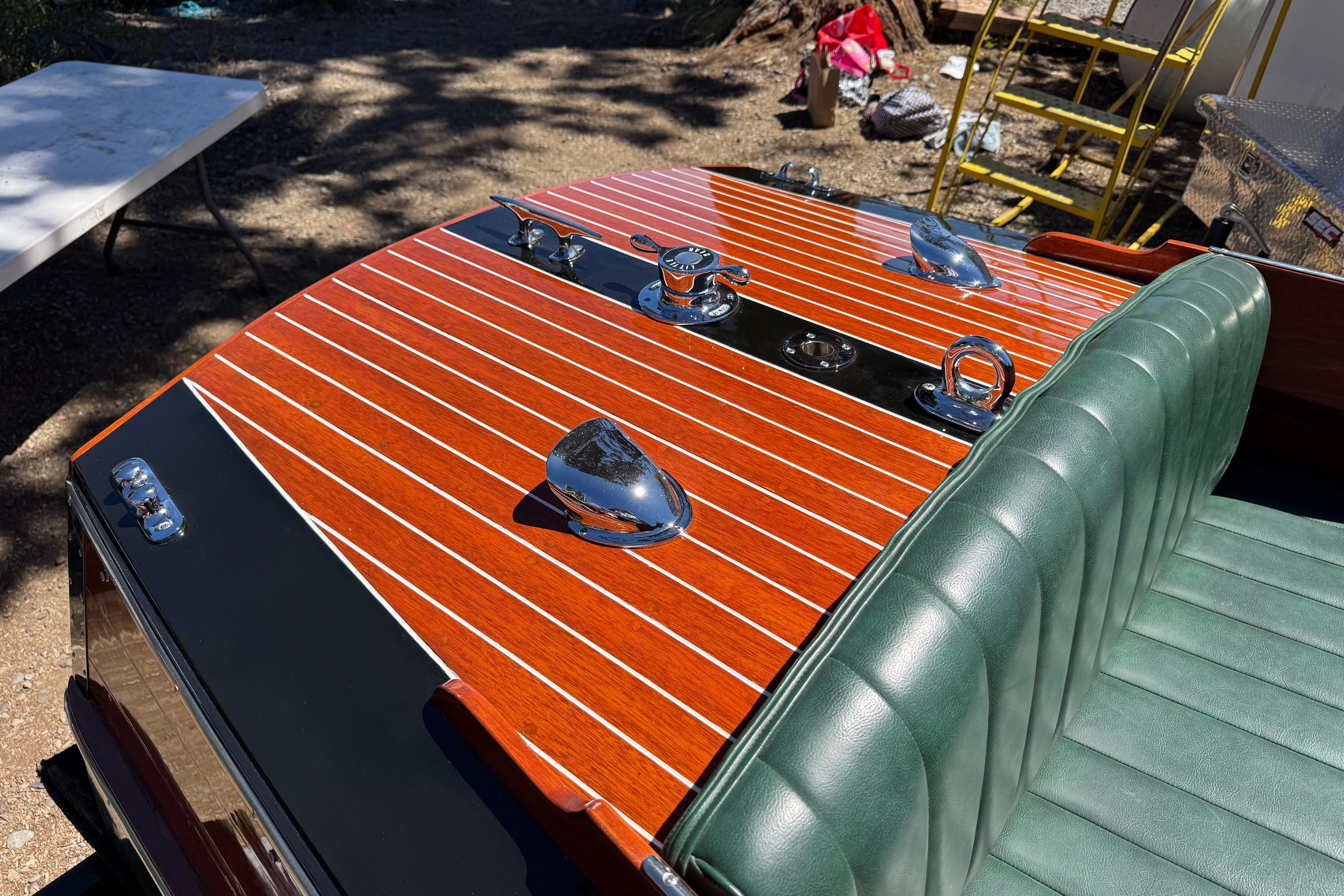1987 Grand Craft Triple Cockpit Runabout with polished wood deck and green leather seats.