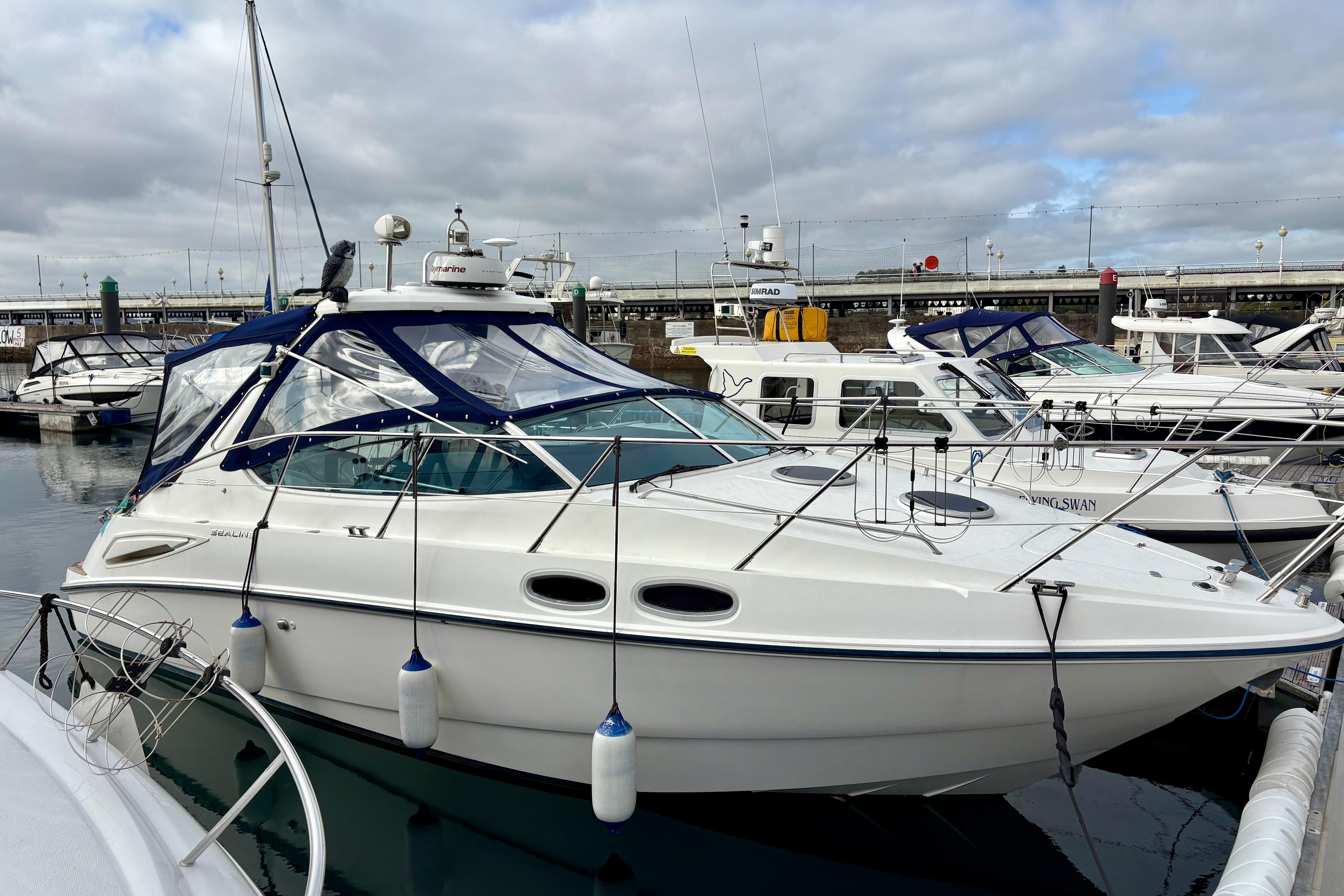 2007 Sealine S29 yacht docked in marina, featuring sleek design and blue canopy.