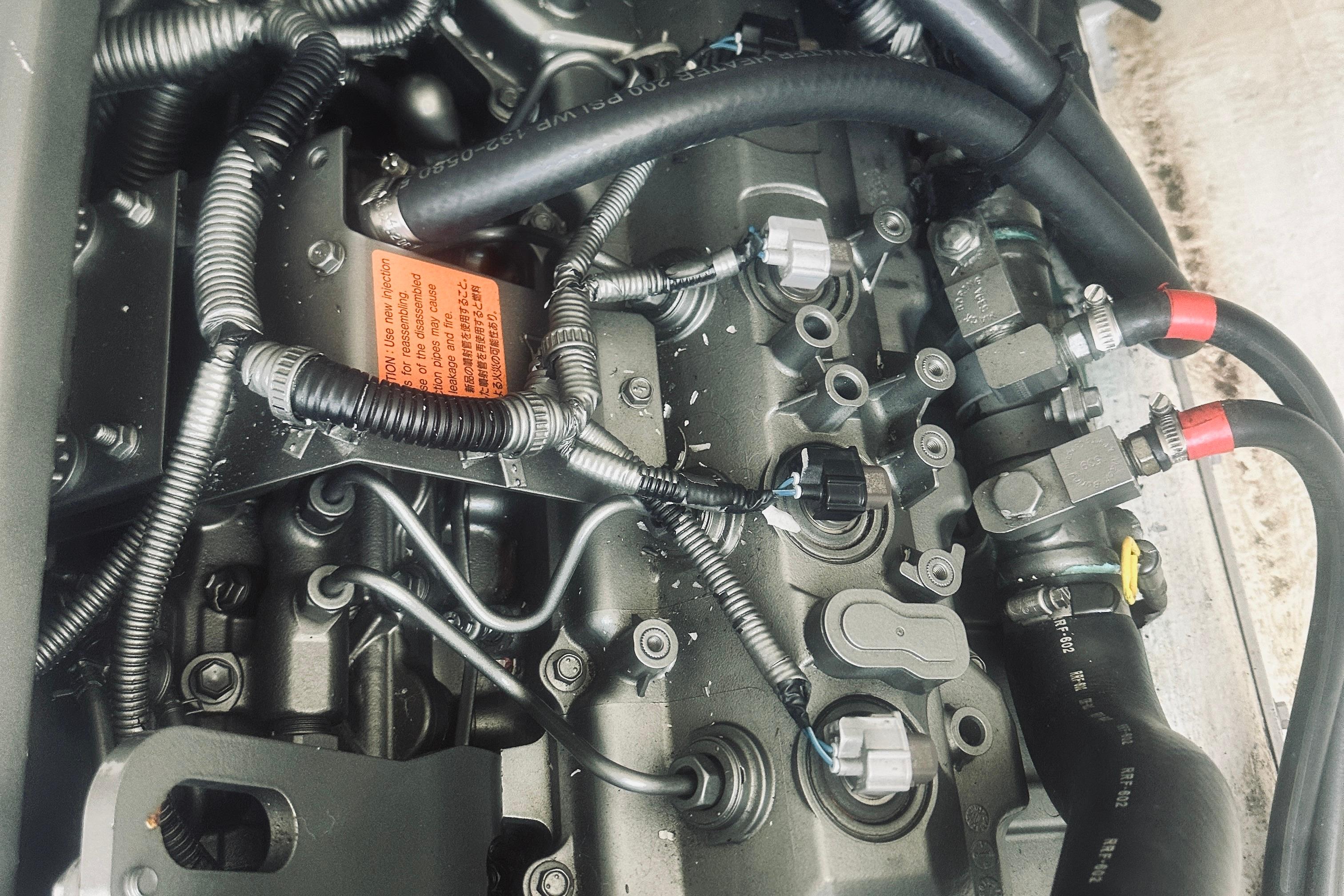 Engine components of a 2013 Back Cove 30 boat, featuring intricate wiring and hoses.