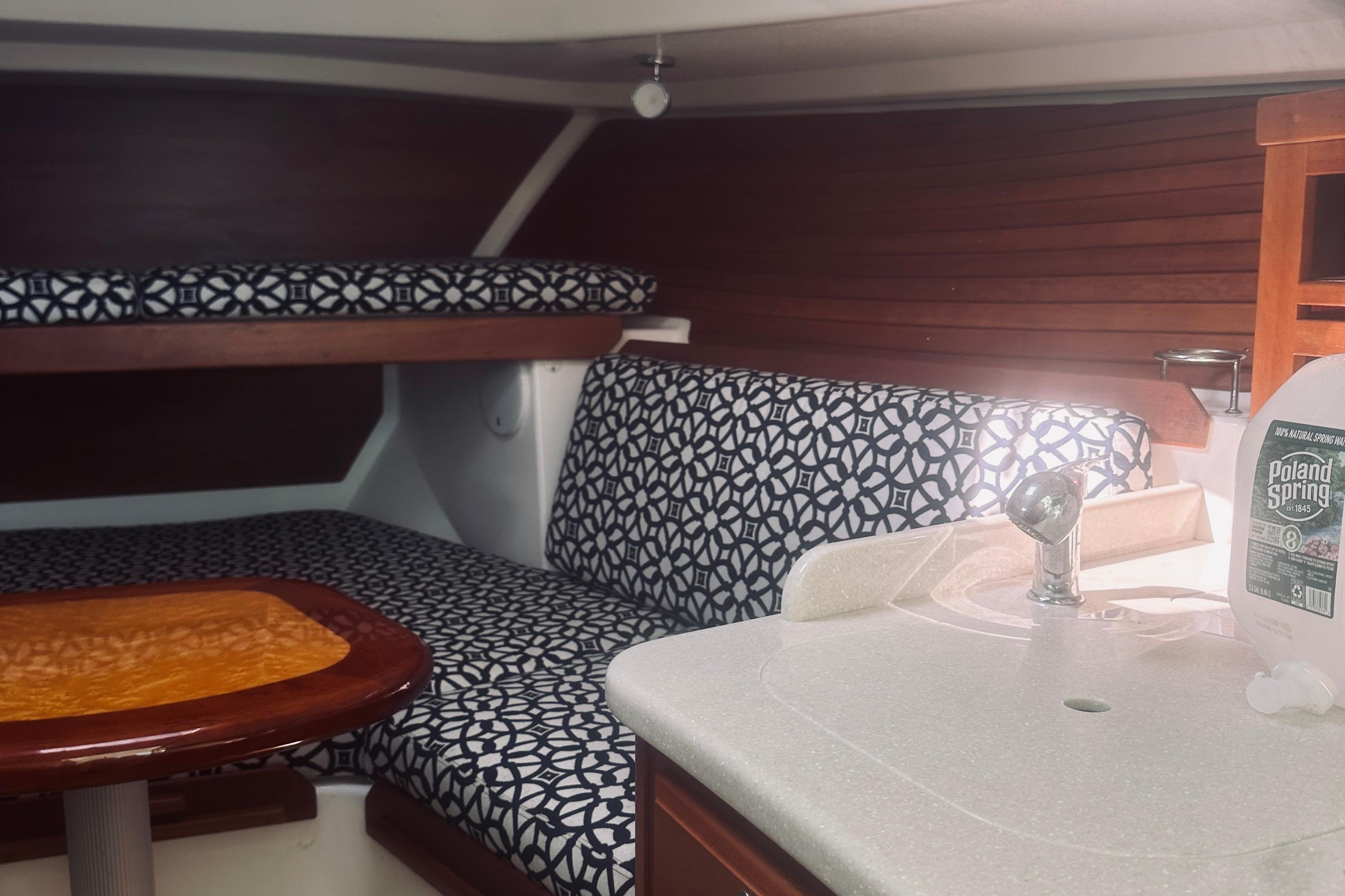 2013 Back Cove 30 interior with patterned seating, wooden table, and compact sink area.