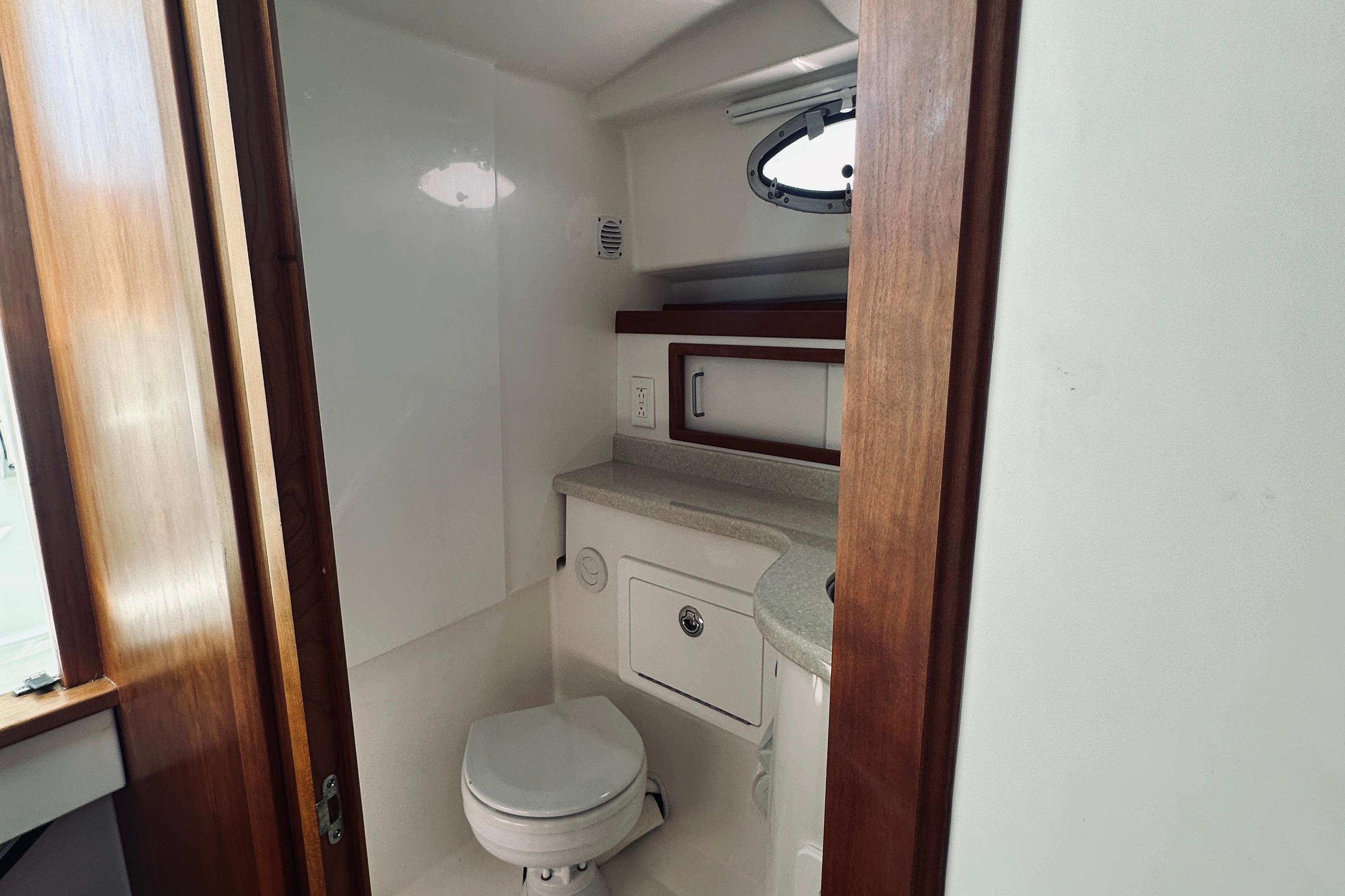 2013 Back Cove 30 yacht bathroom with toilet, sink, and wooden accents.