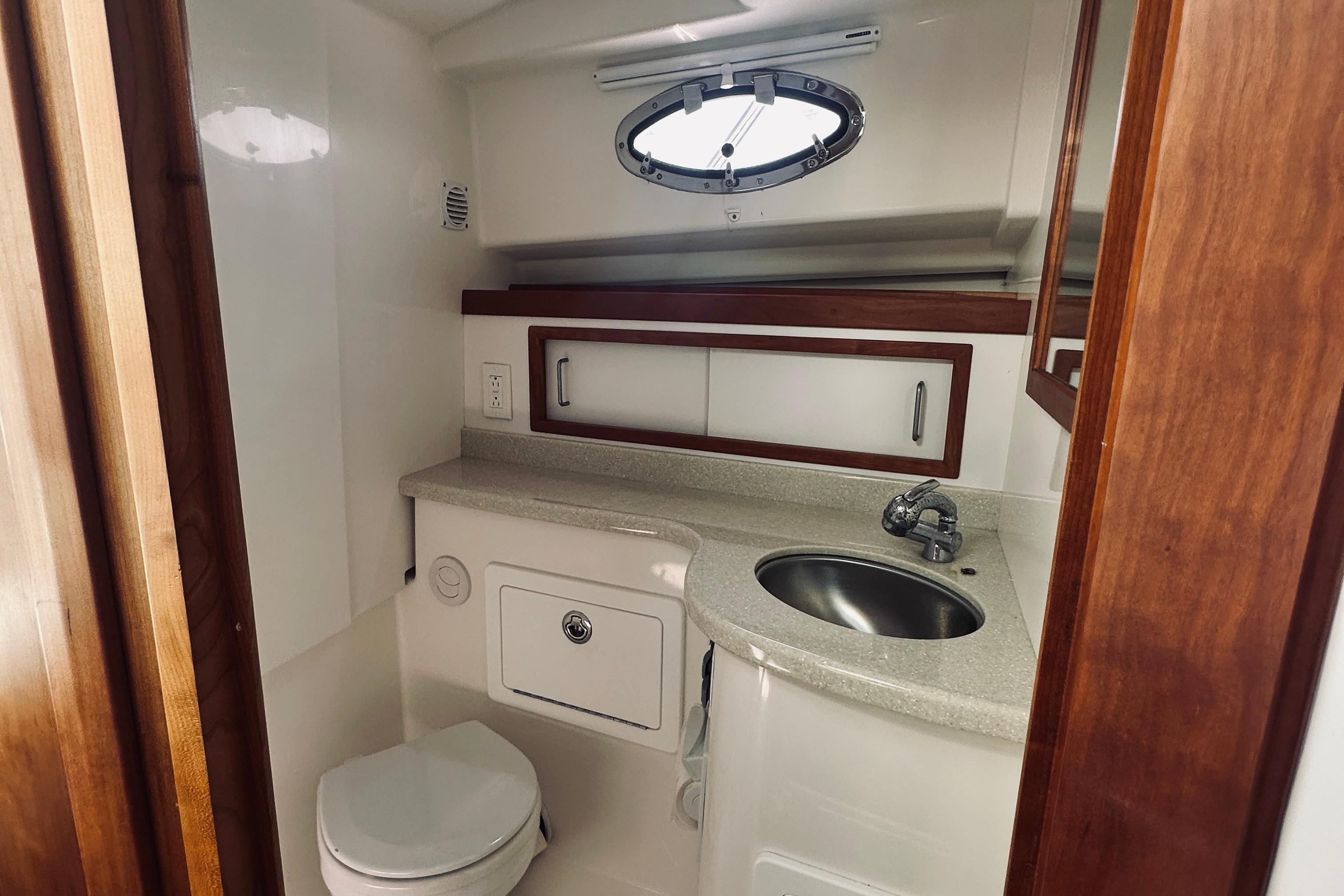 2013 Back Cove 30 yacht bathroom with sink, toilet, and porthole window.