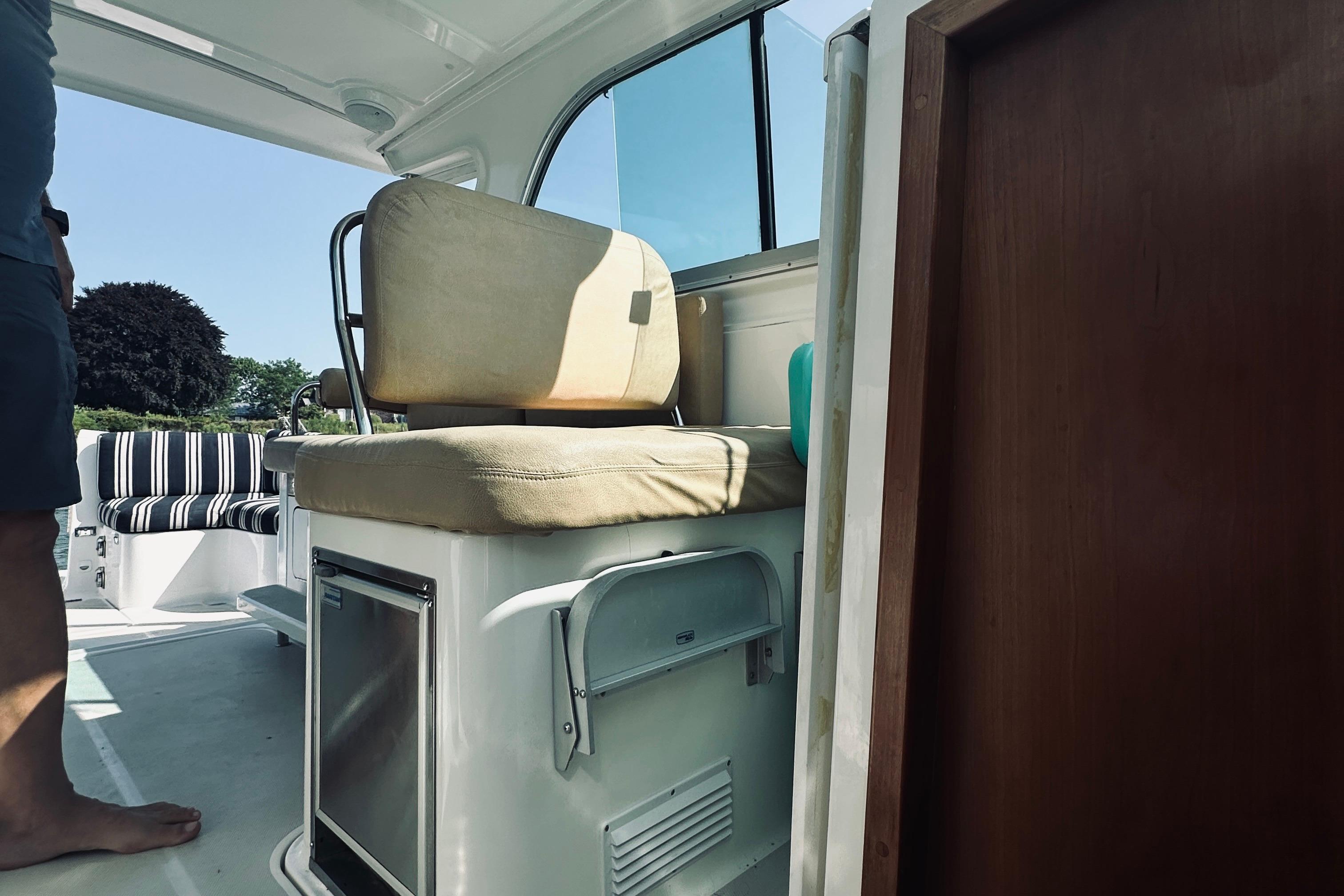 Interior of a 2013 Back Cove 30 boat, featuring seating and a compact fridge.
