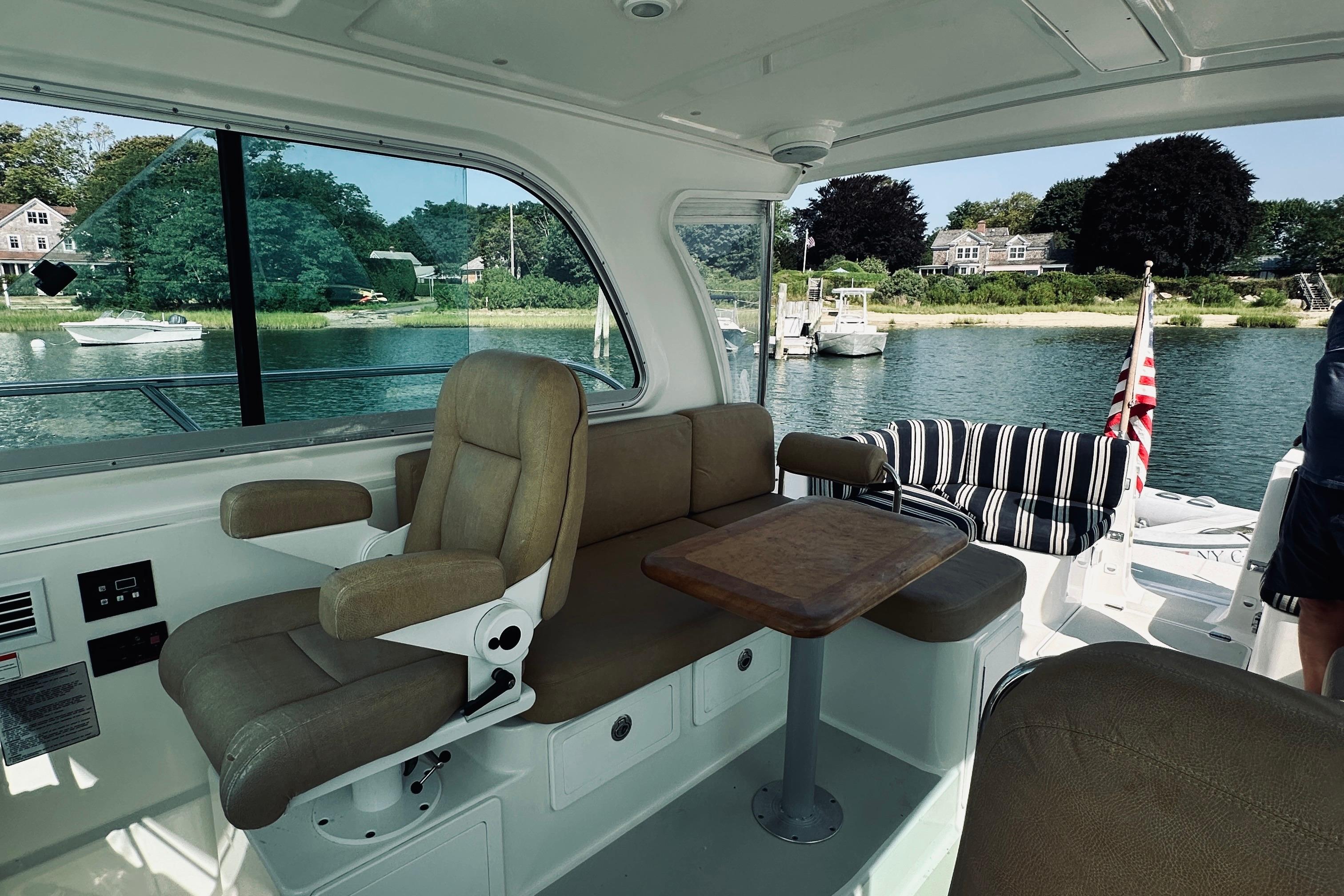 Interior of 2013 Back Cove 30 boat with seating and table, overlooking serene waterfront.