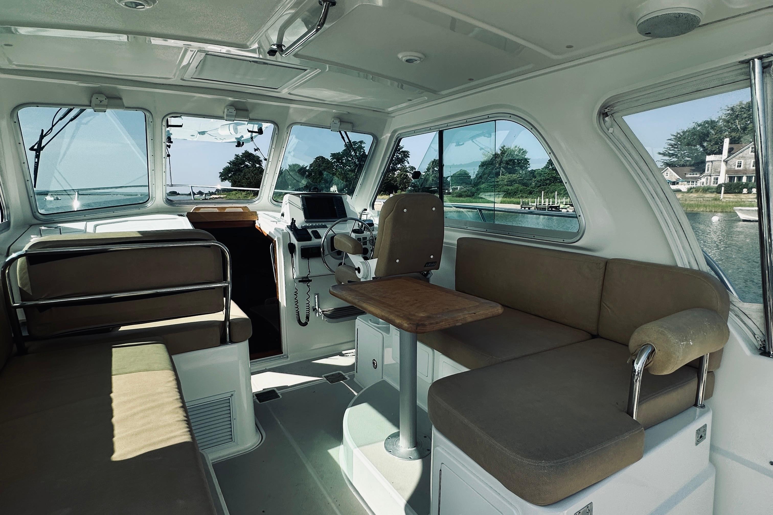 Interior of 2013 Back Cove 30 boat with seating and helm, overlooking scenic waterway.