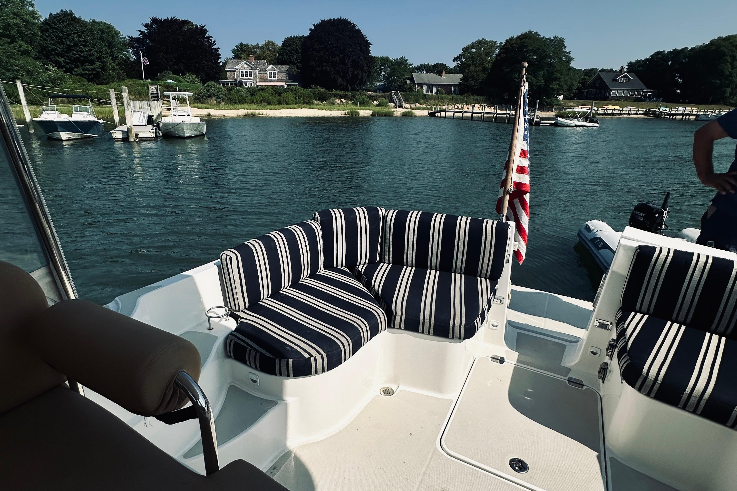 2013 Back Cove 30 boat with striped seating, docked in a scenic marina.