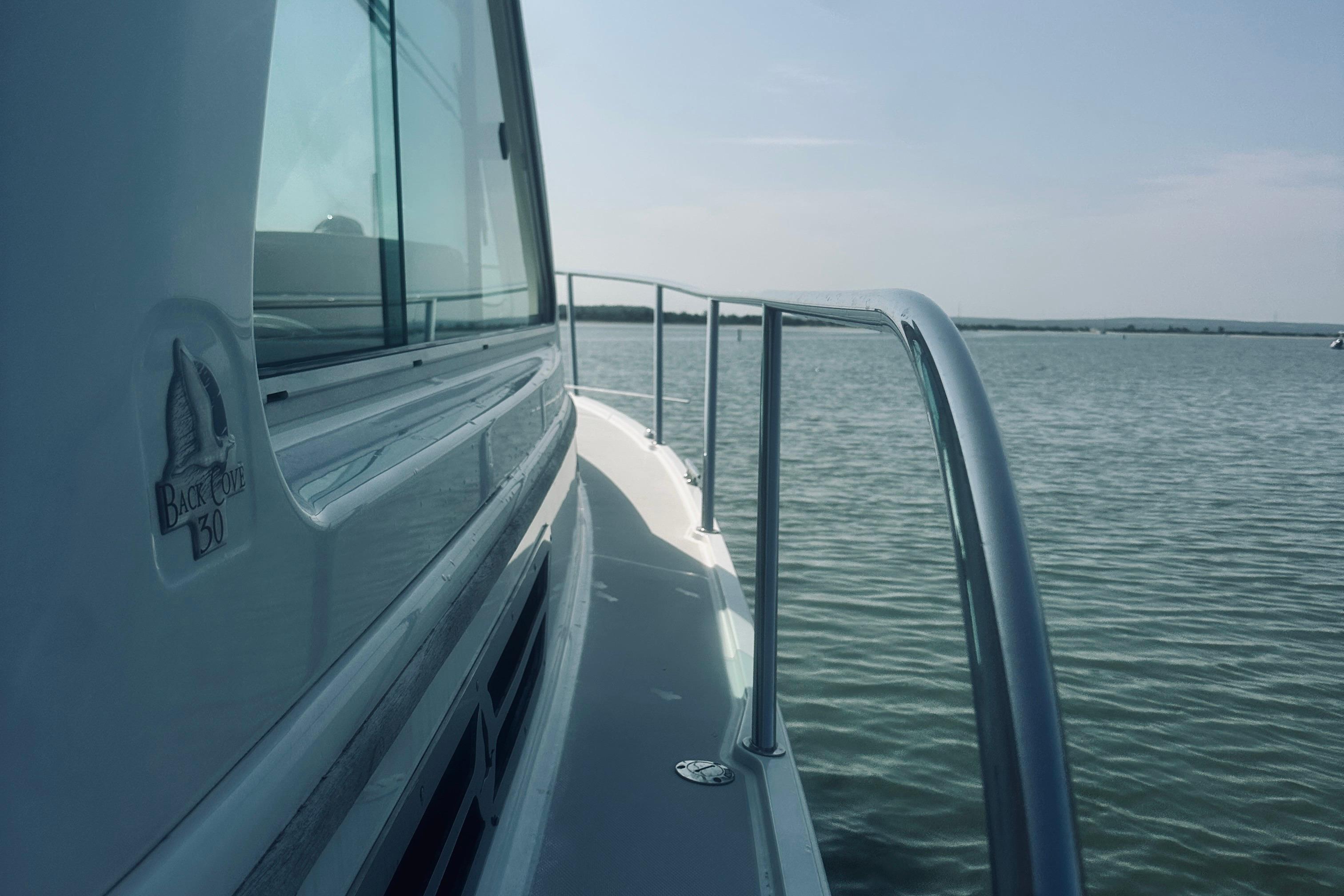 2013 Back Cove 30 boat on calm water, side view with railing and logo.
