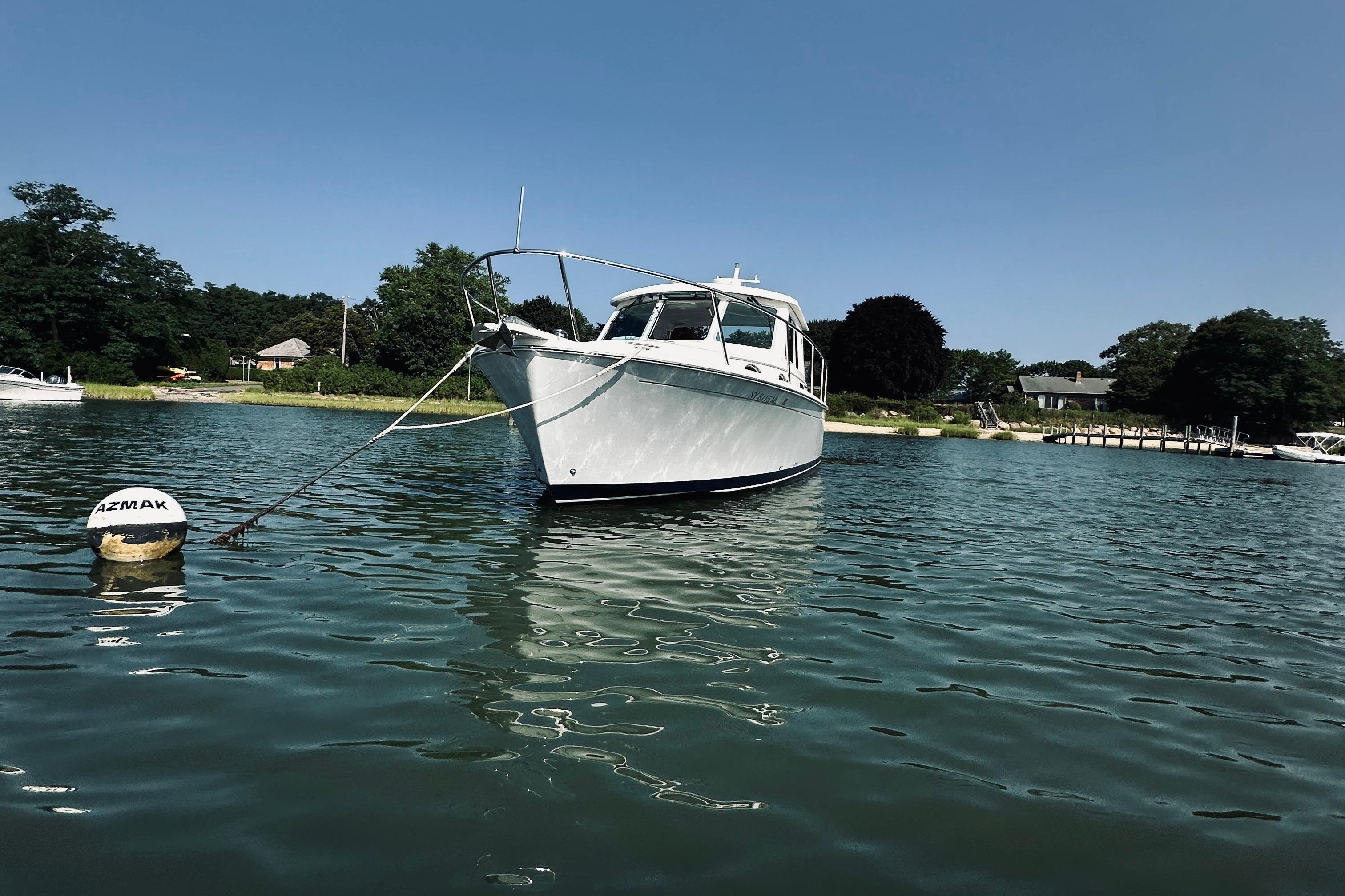2013 Back Cove 30 boat anchored in calm waters near a scenic shoreline.