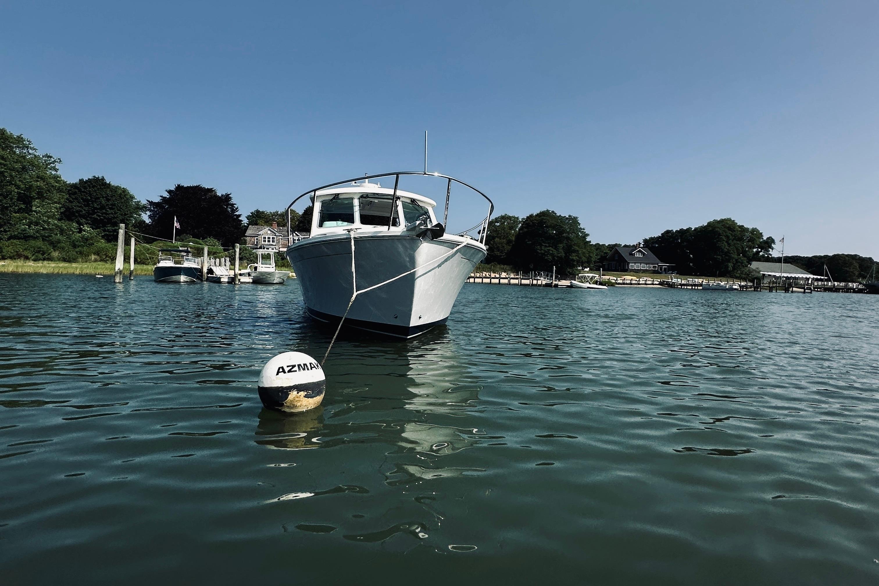 2013 Back Cove 30 boat moored in a serene harbor with clear blue skies.