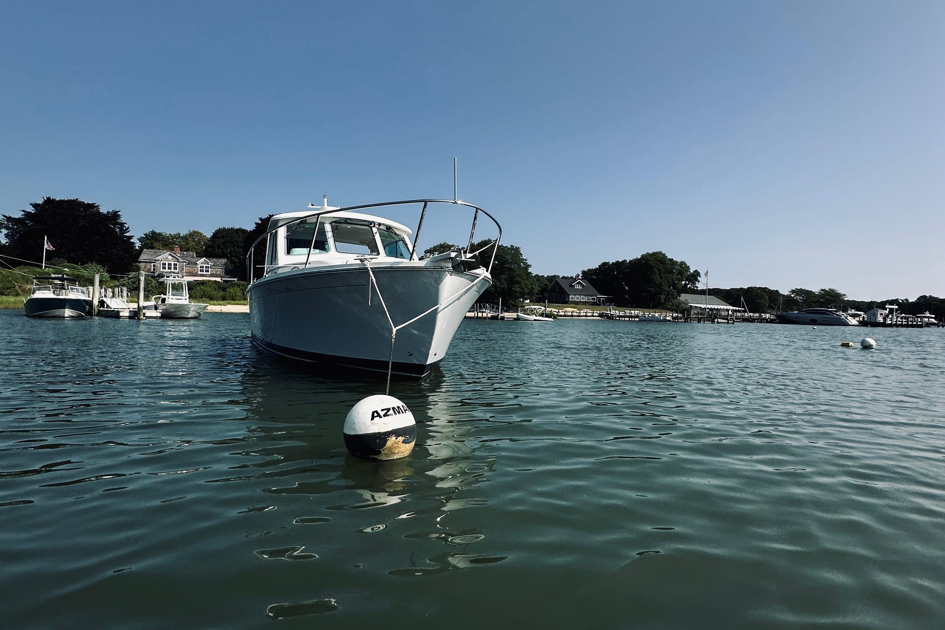 2013 Back Cove 30 boat moored in a scenic harbor with clear blue skies.