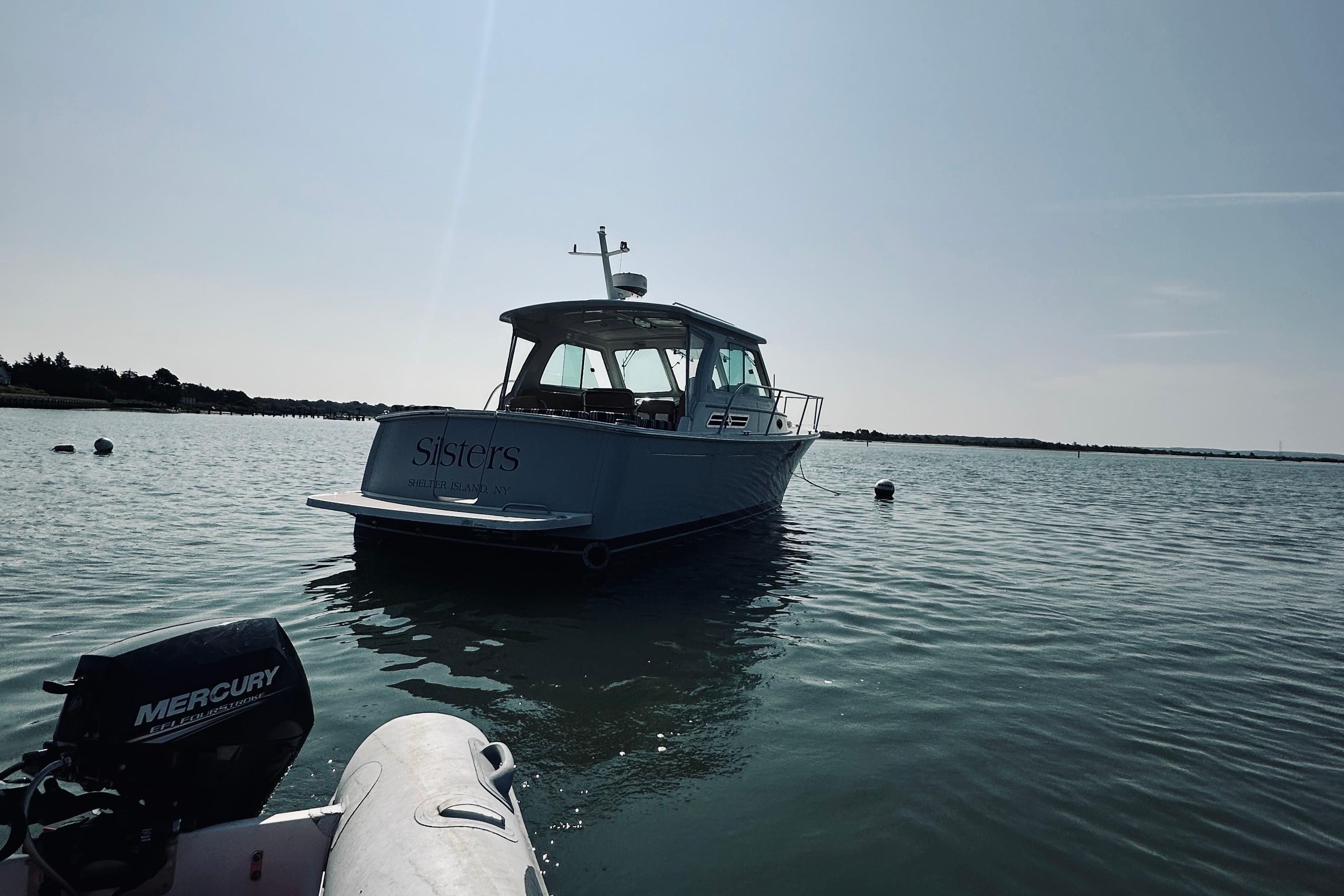 2013 Back Cove 30 boat named u0022Sistersu0022 on calm water, with Mercury engine nearby.