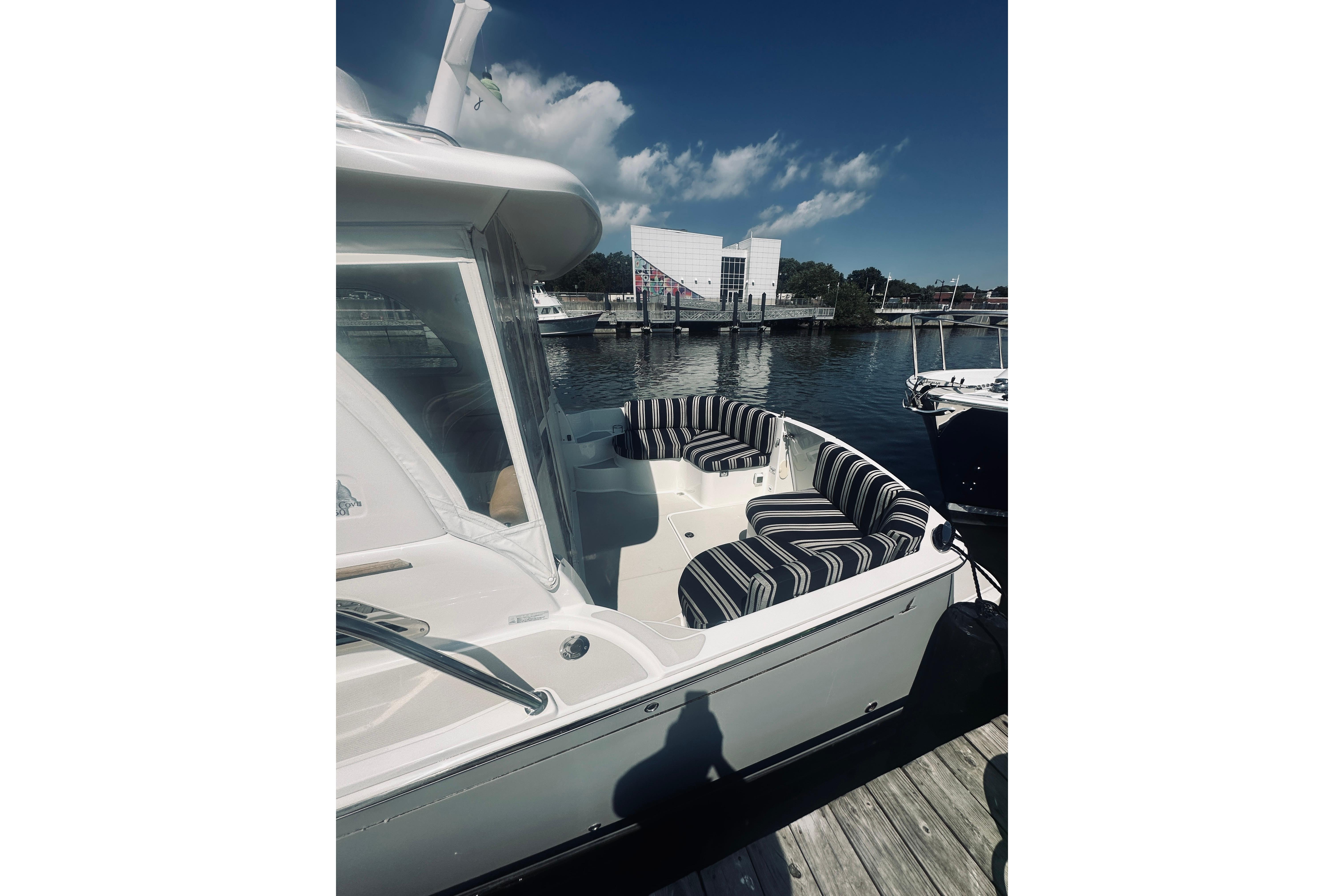 2013 Back Cove 30 boat with striped seating docked at a marina.
