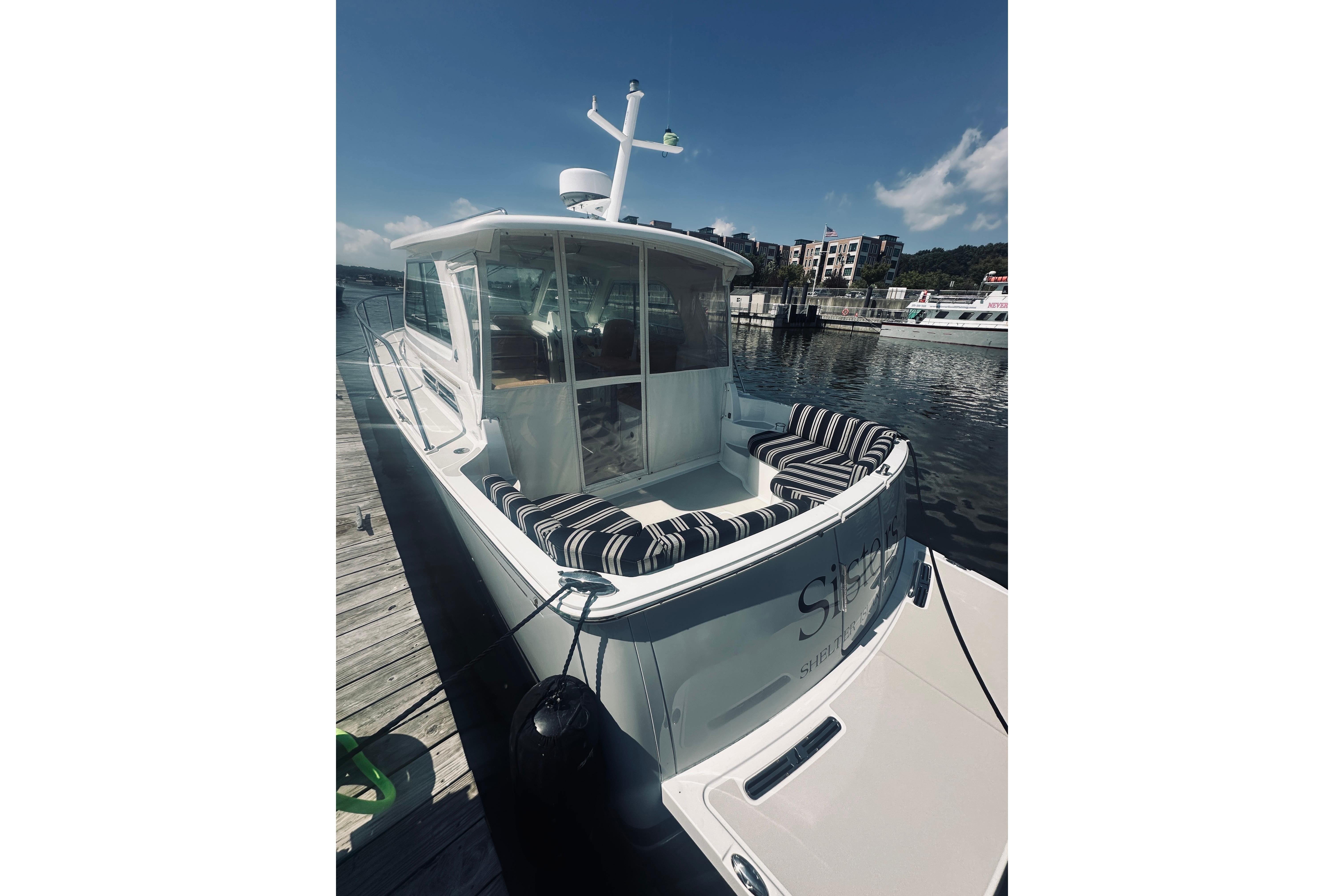 2013 Back Cove 30 boat docked, featuring striped seating and a sleek design.