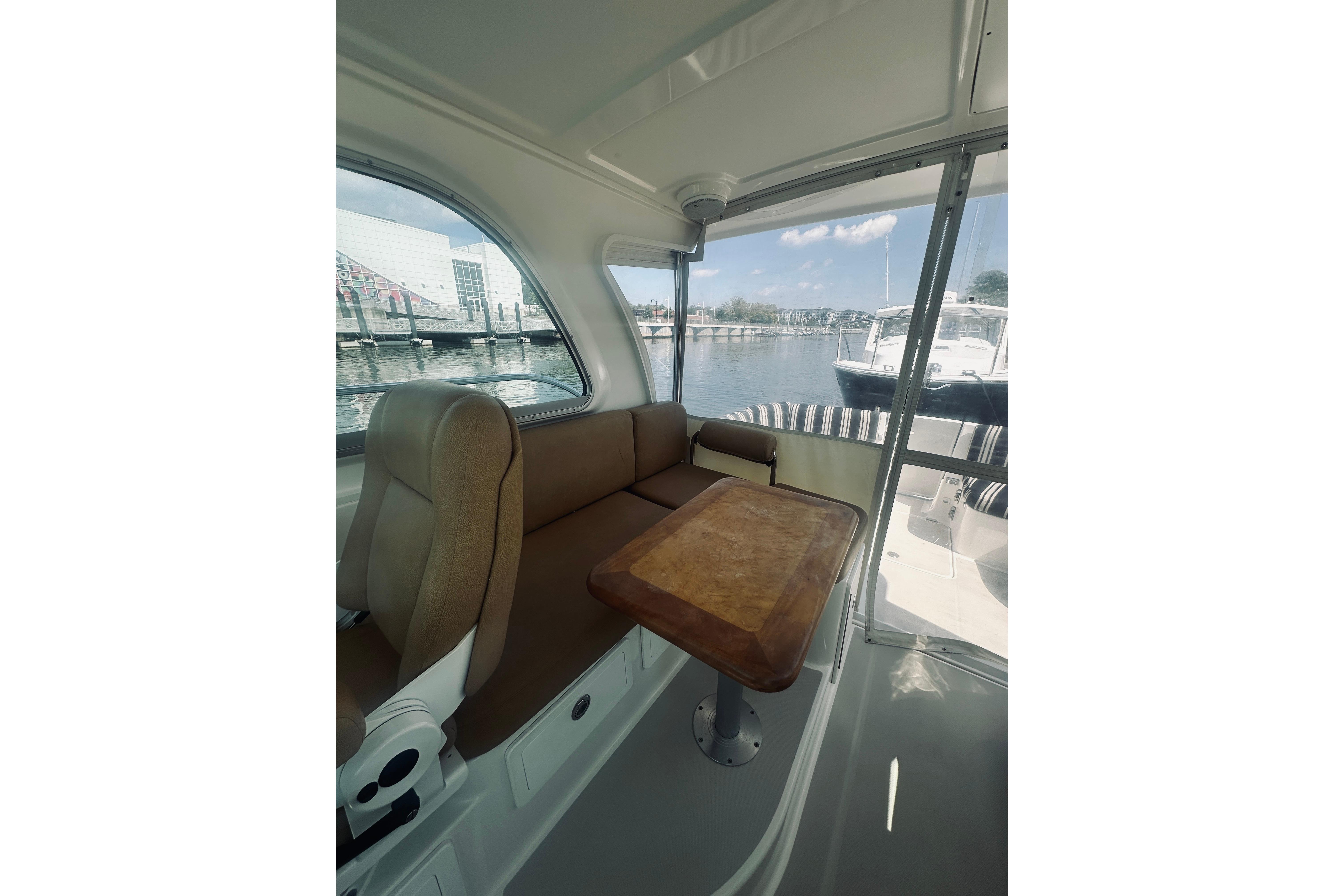 Interior view of 2013 Back Cove 30 boat with seating and table by the water.