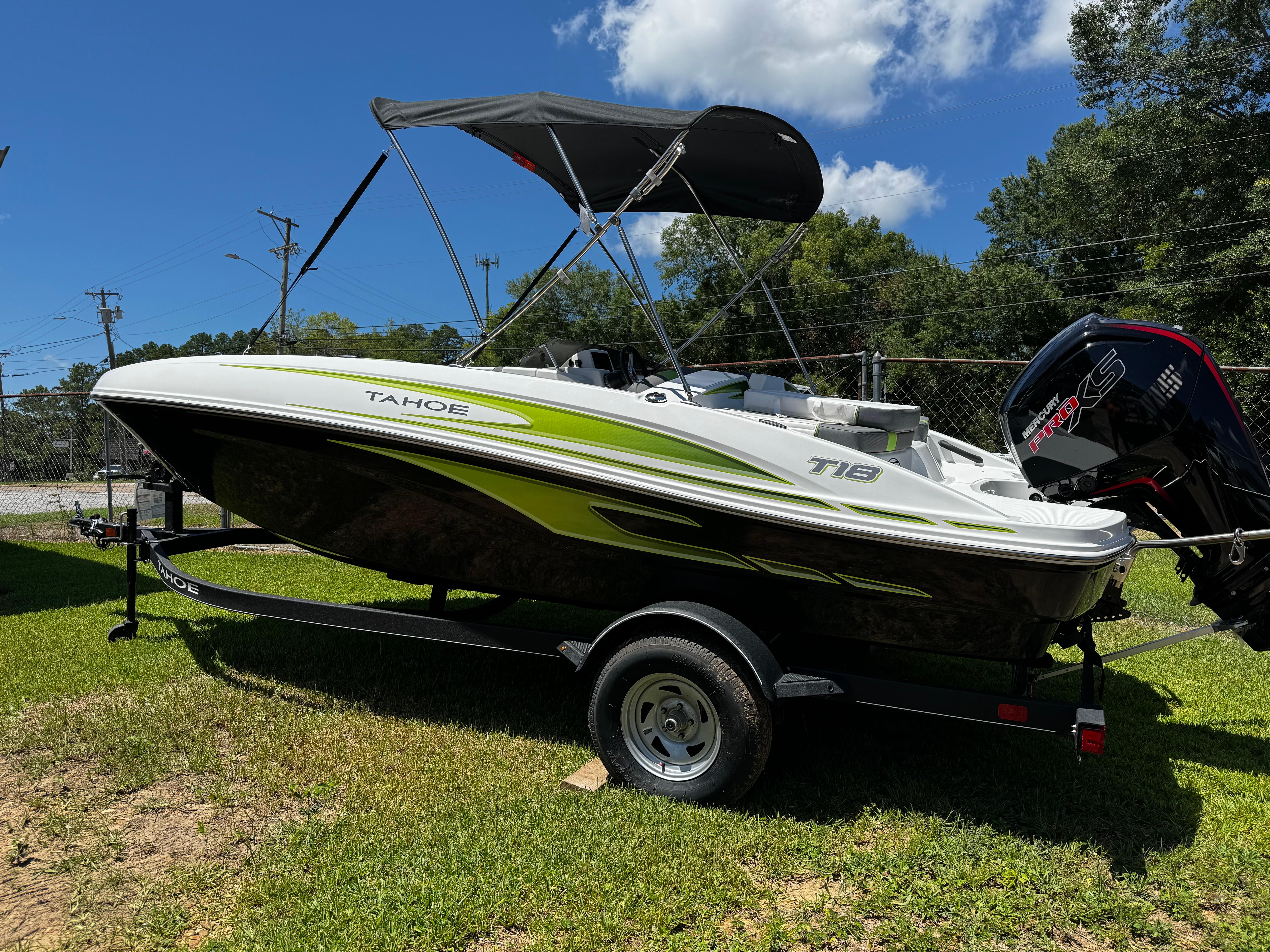 2024 Tahoe T18 boat on trailer, green and white design, parked on grass under blue sky.