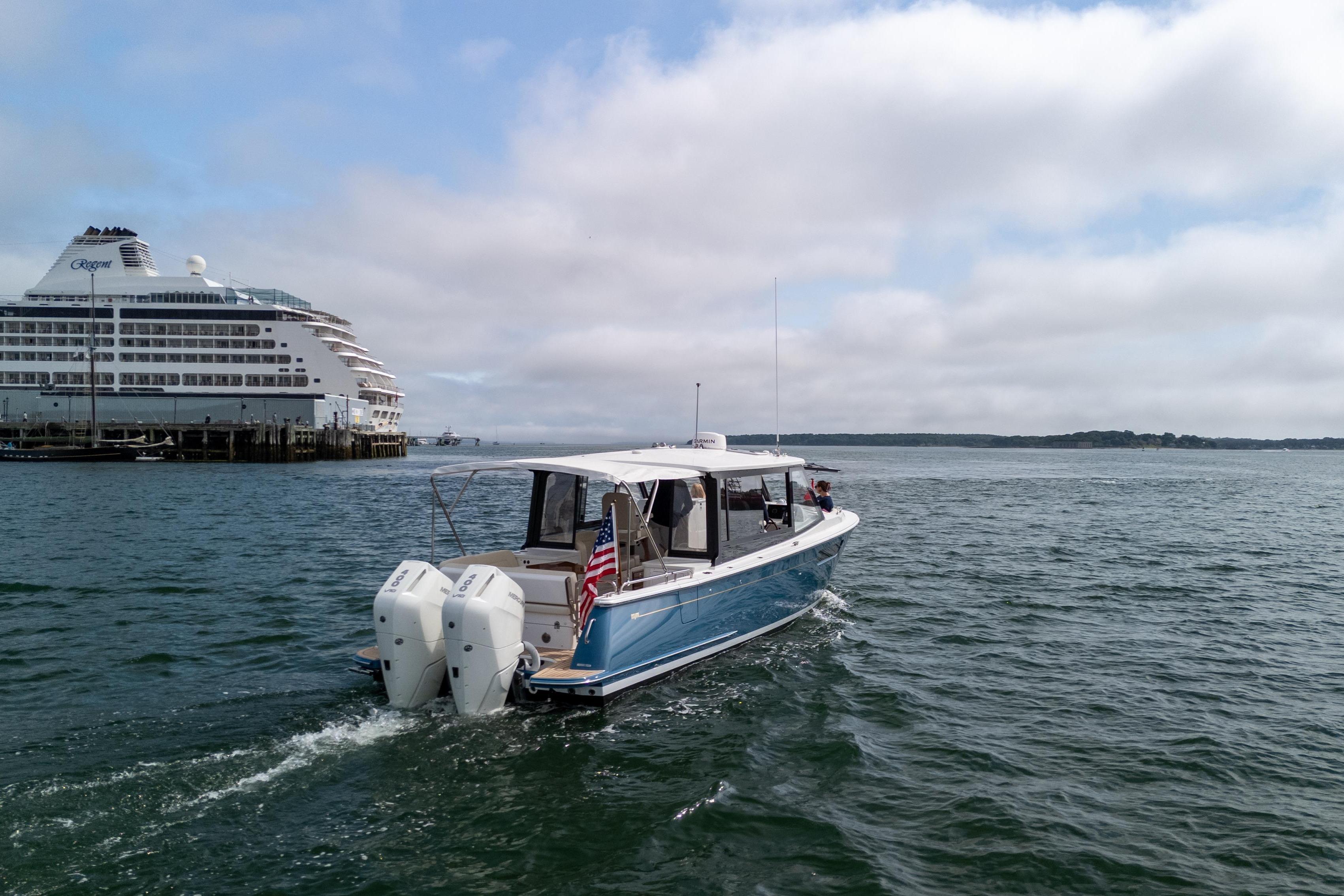 2025 MJM 3 boat cruising near a large cruise ship on a sunny day.