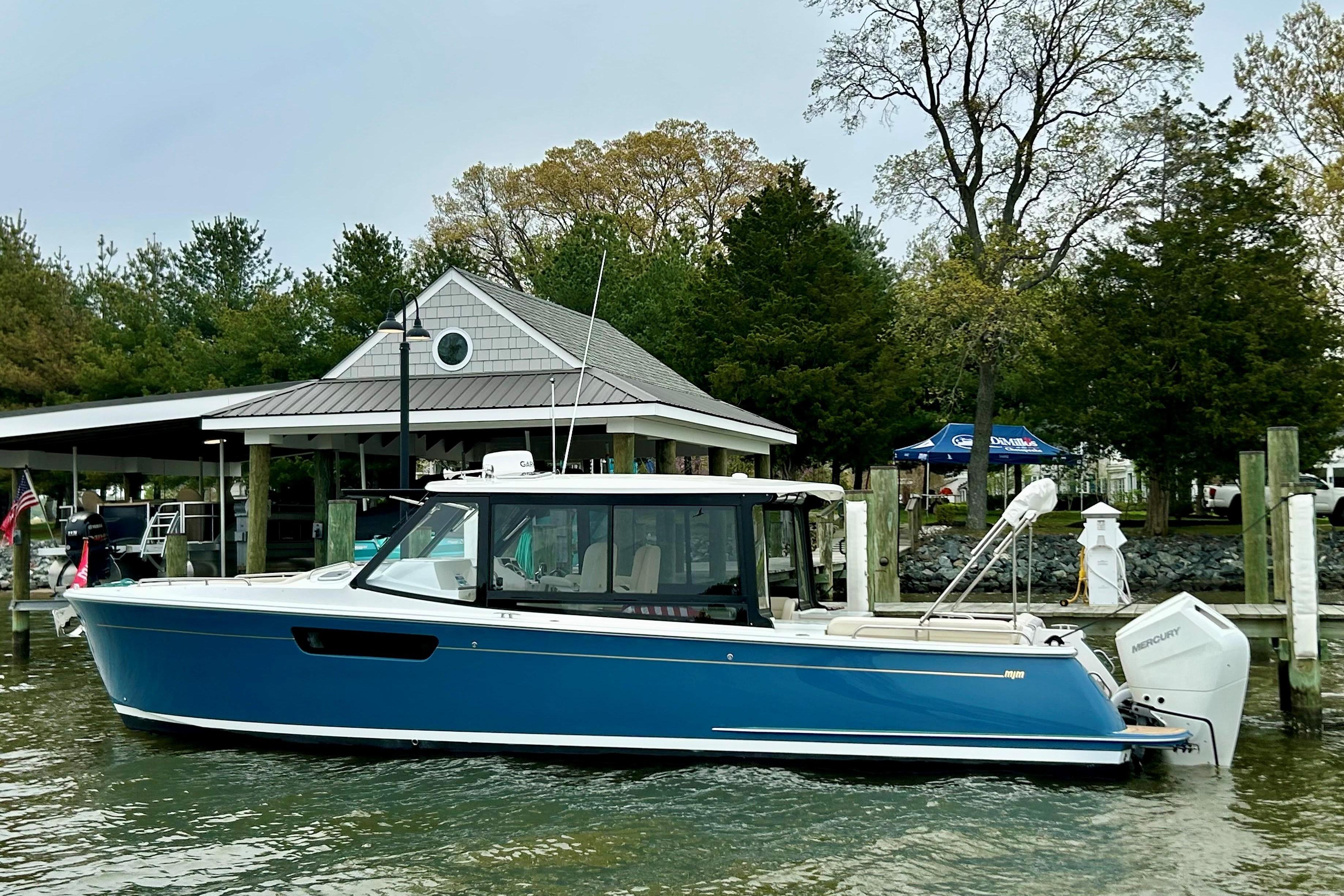 2025 MJM 3 boat docked at marina, featuring sleek blue design and modern outboard motor.