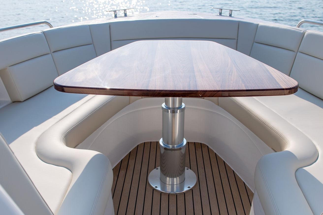 Luxurious seating area on 2025 MJM 3 boat with wooden table and cushioned seats.