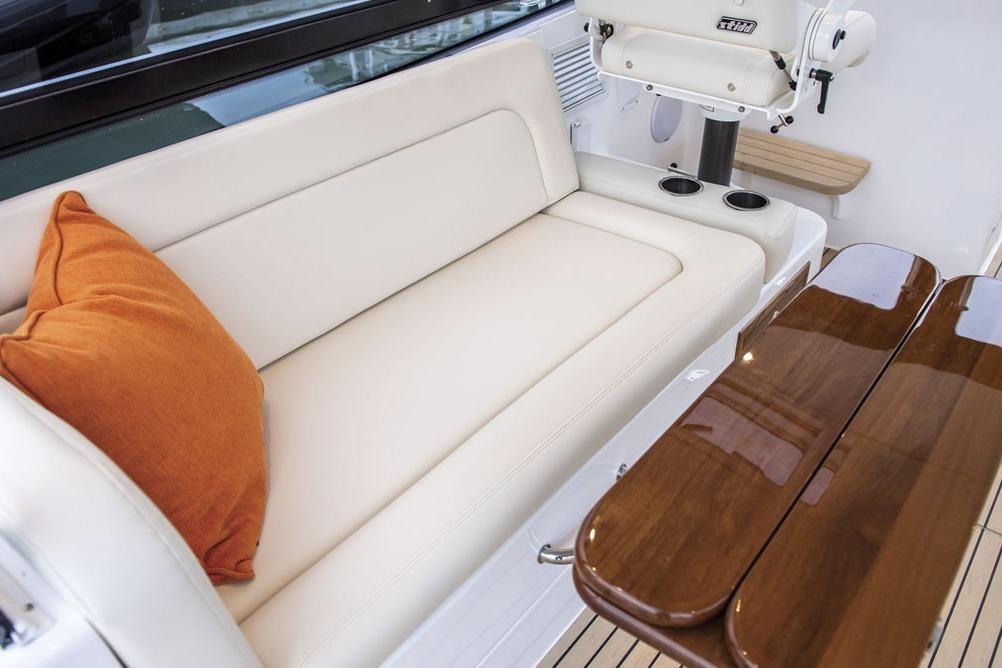 Luxurious seating area on 2025 MJM 3 boat with orange pillow and wooden table.