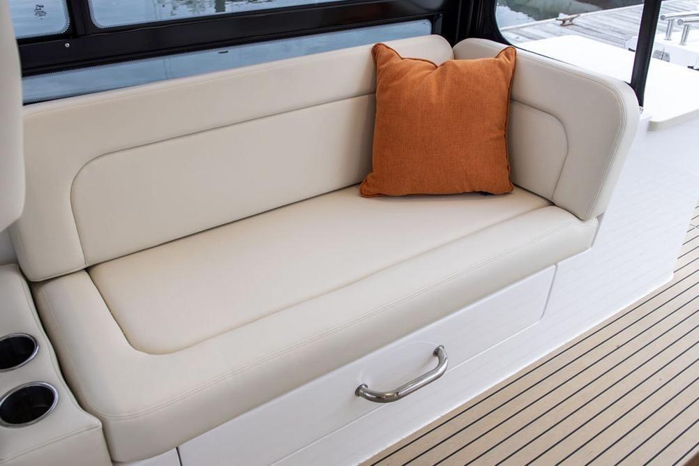 Luxurious seating on 2025 MJM 3 boat with orange cushion and cup holders.