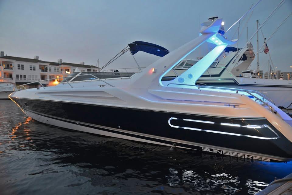 1994 Sunseeker Apache 45 yacht docked at marina, illuminated with blue lights.