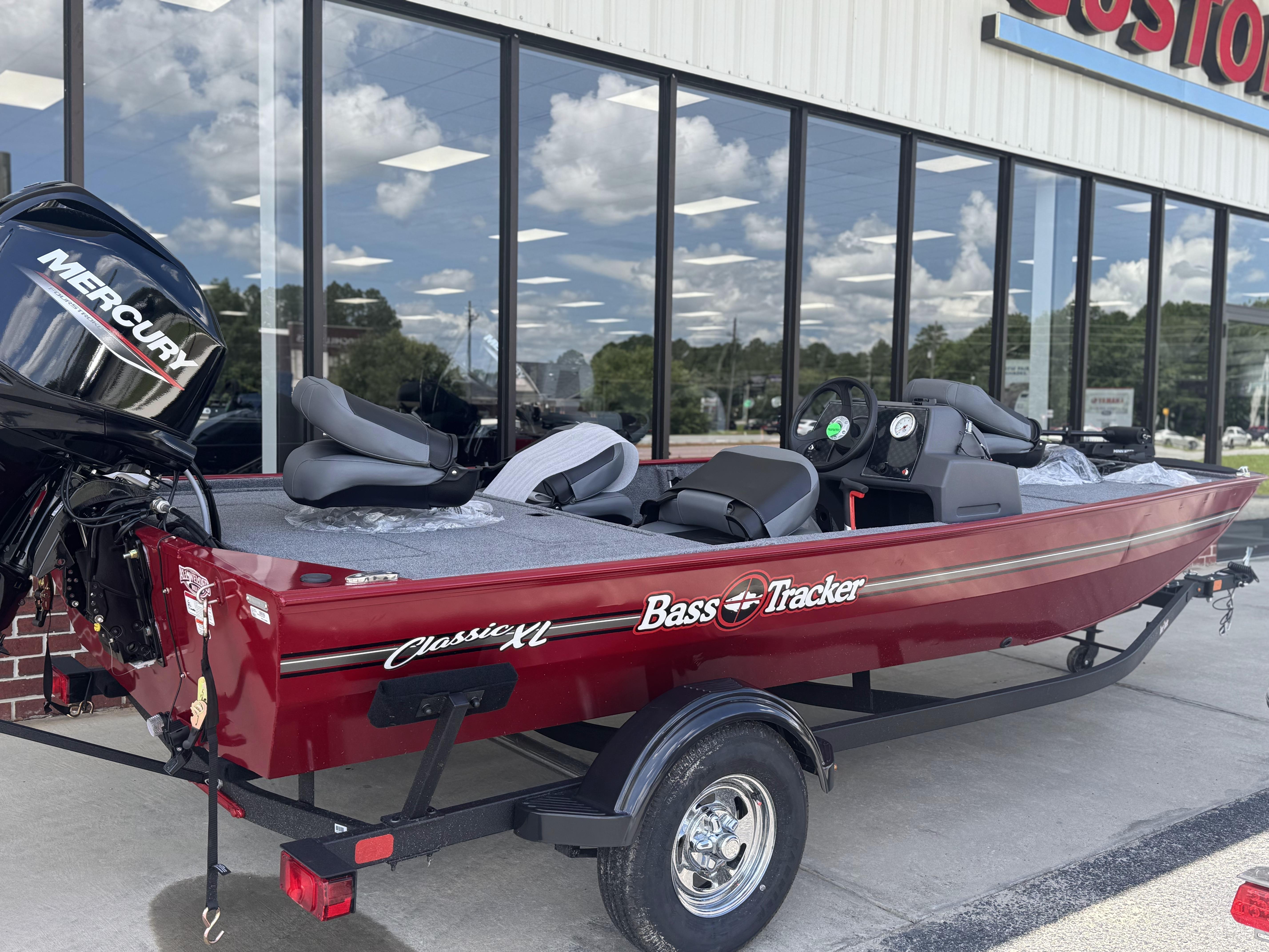 2025 Tracker Bass Tracker Classic XL boat with Mercury engine, parked outside a store.