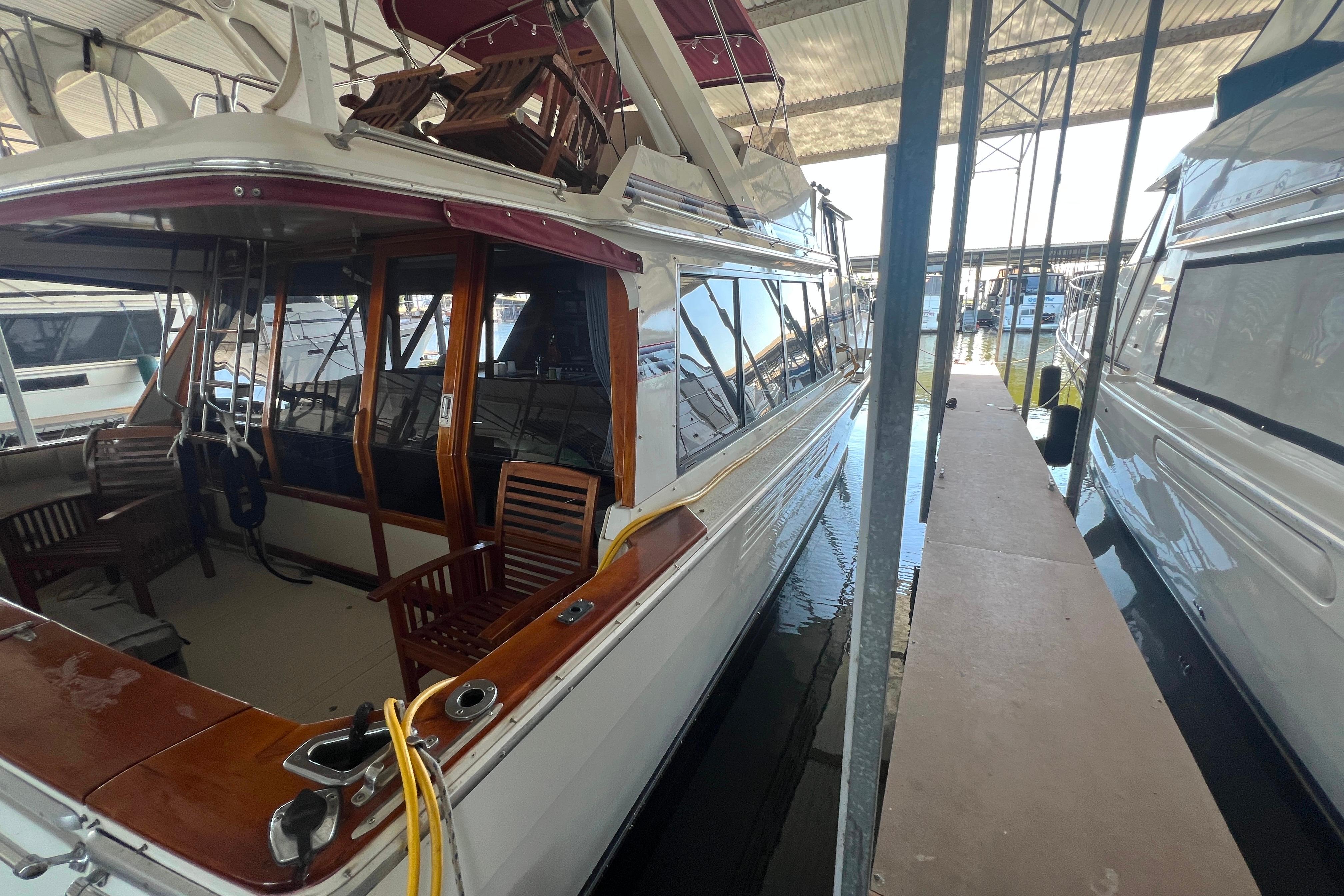 1986 Bayliner 4550 Motoryacht docked in marina, featuring wooden deck and seating area.