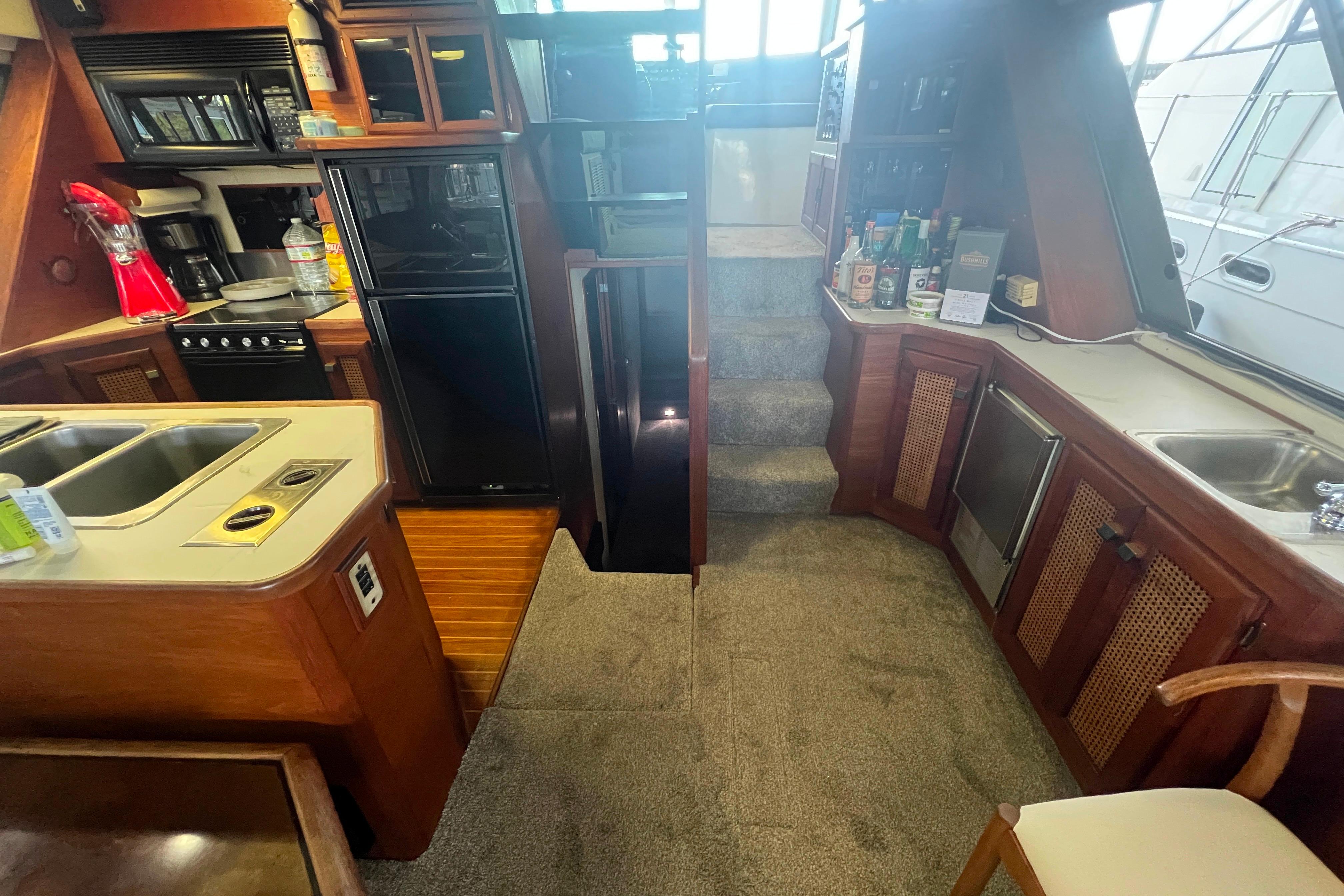 Interior of 1986 Bayliner 4550 Motoryacht with kitchen and stairs, featuring wood cabinetry.