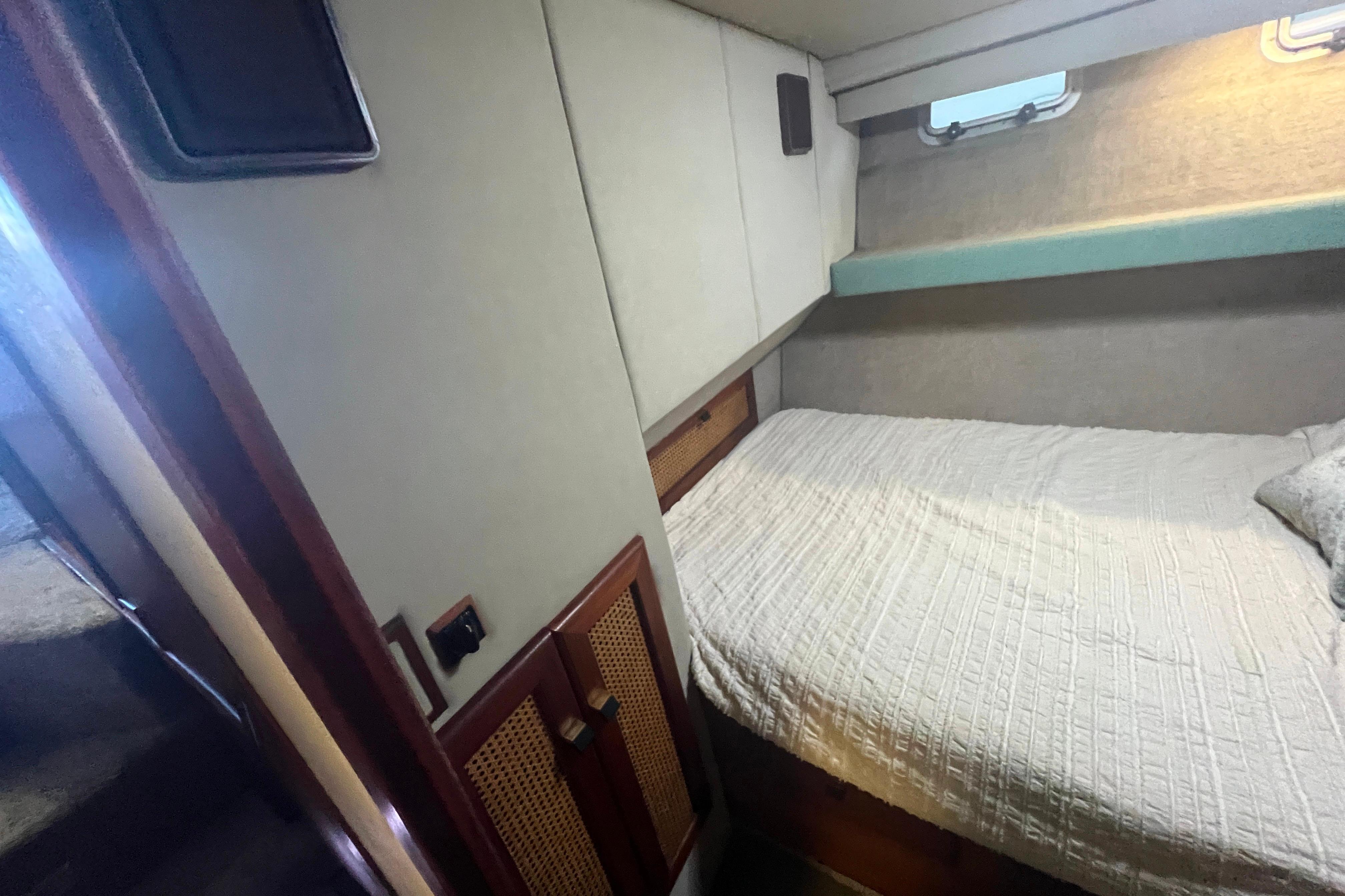 1986 Bayliner 4550 Motoryacht cabin with bed, window, and storage cabinets.