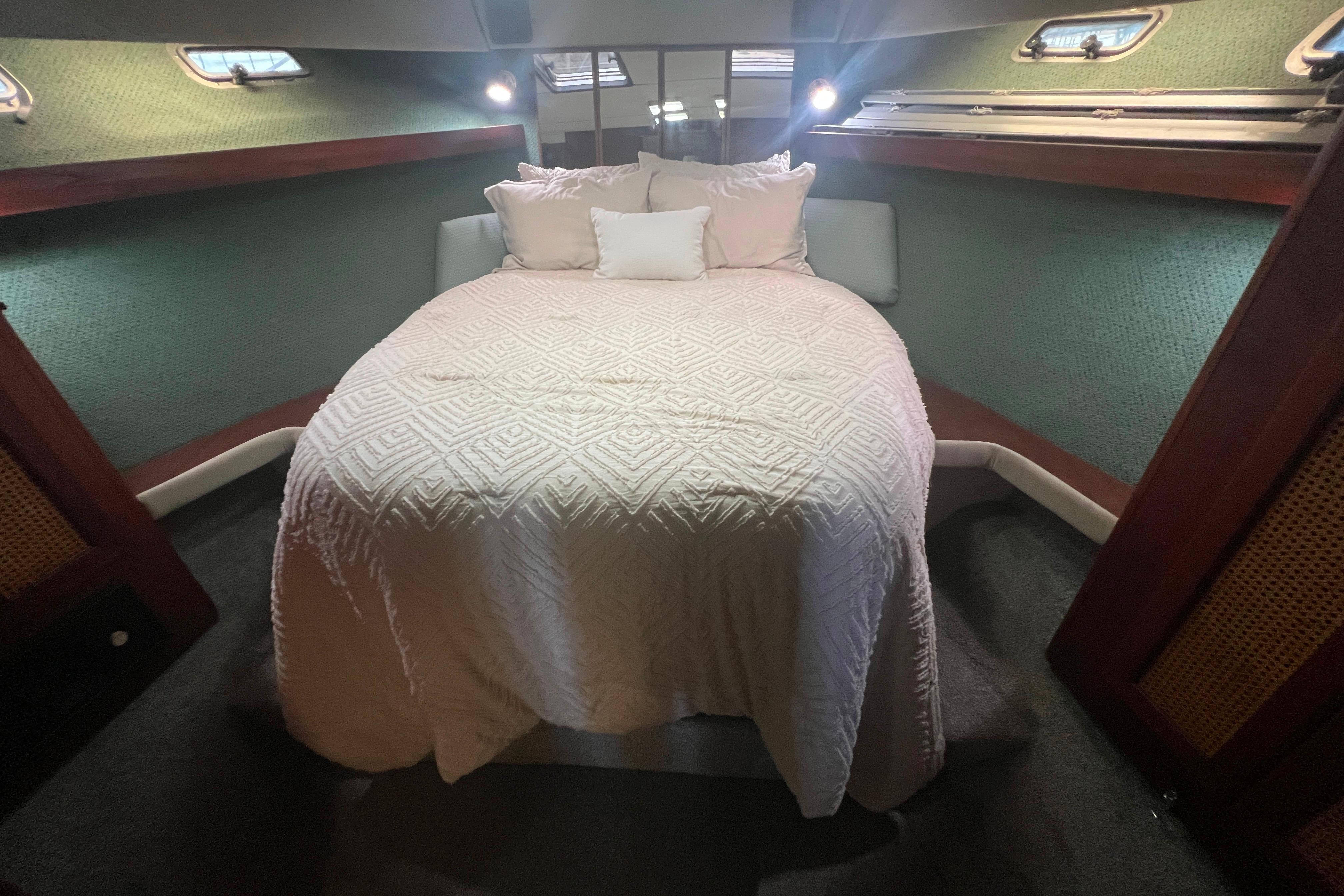 Cozy bedroom in 1986 Bayliner 4550 Motoryacht with elegant bedding and ambient lighting.