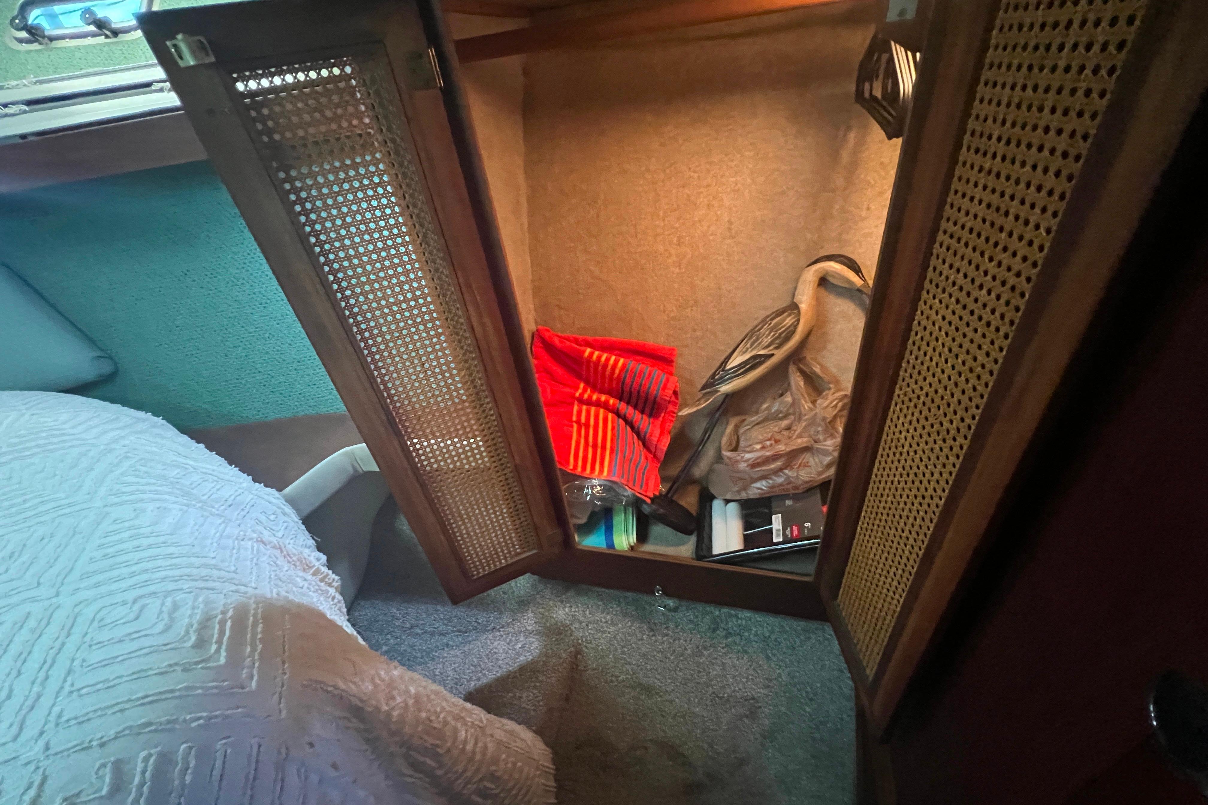 Open cabinet in 1986 Bayliner 4550 Motoryacht with decorative items and textiles inside.